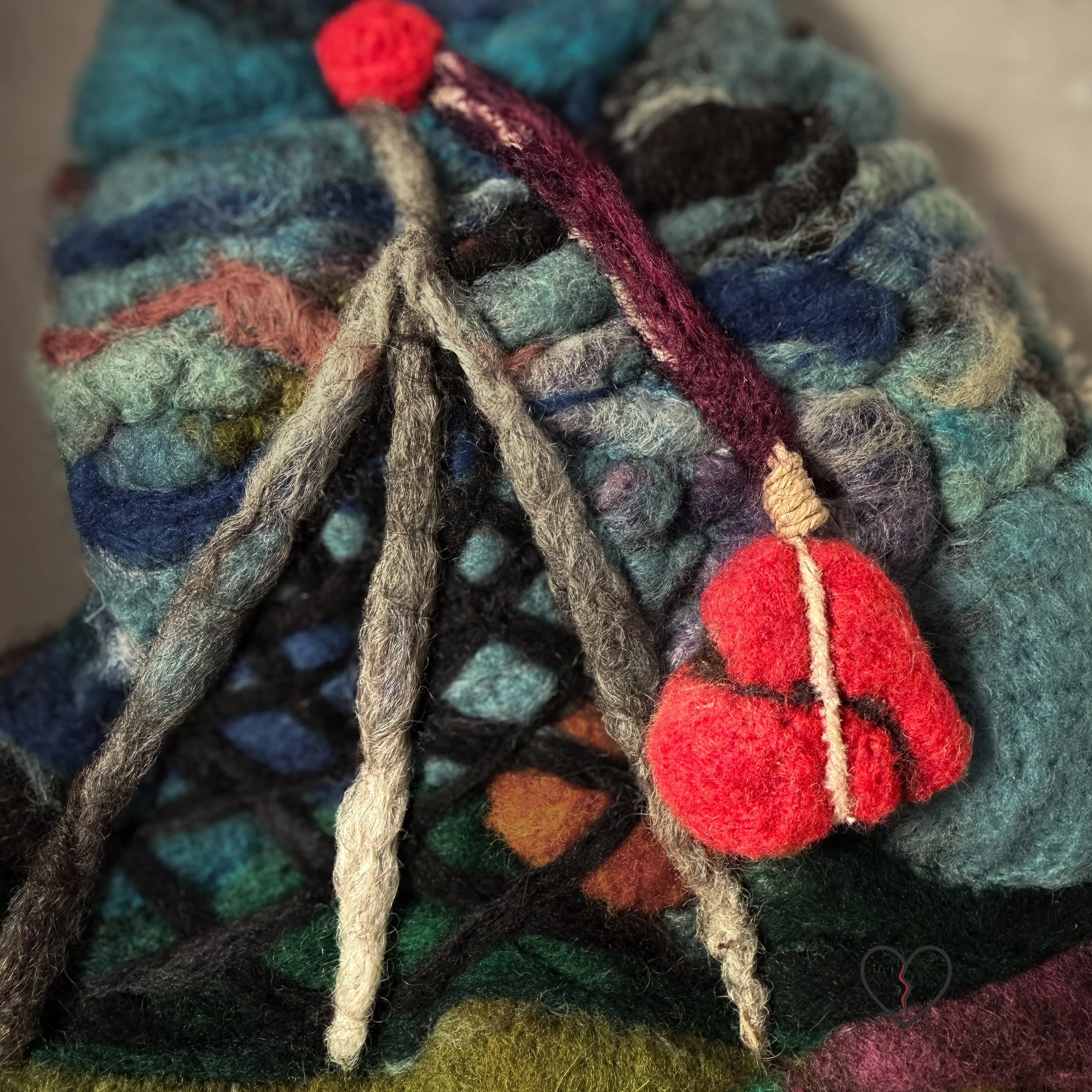 Needle felted wool wall art showing a rural landscape disrupted by a cell tower with a red broken heart hanging beneath it.