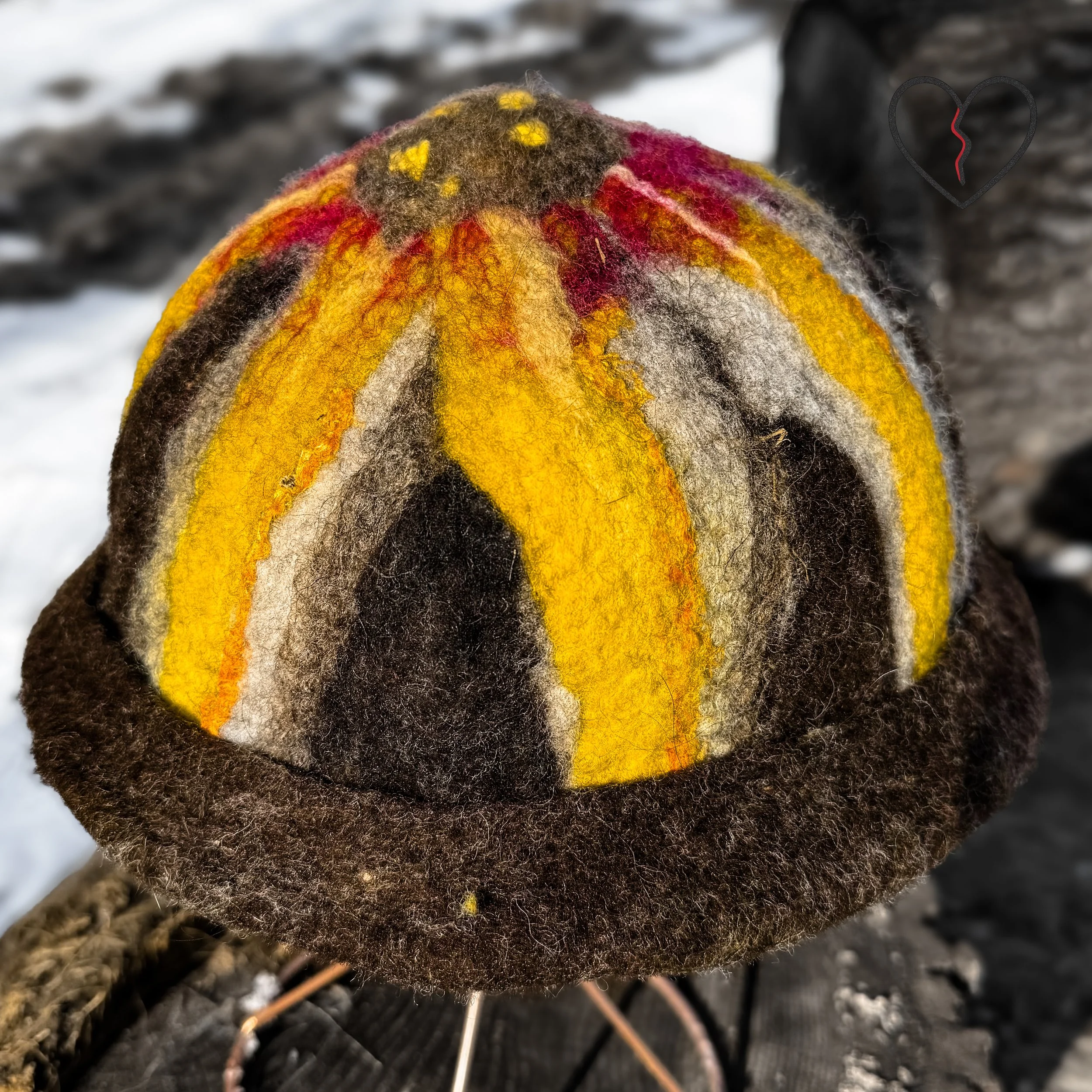 Back view of handmade wool acorn hat with warm yellow and earth tone fiber striping.