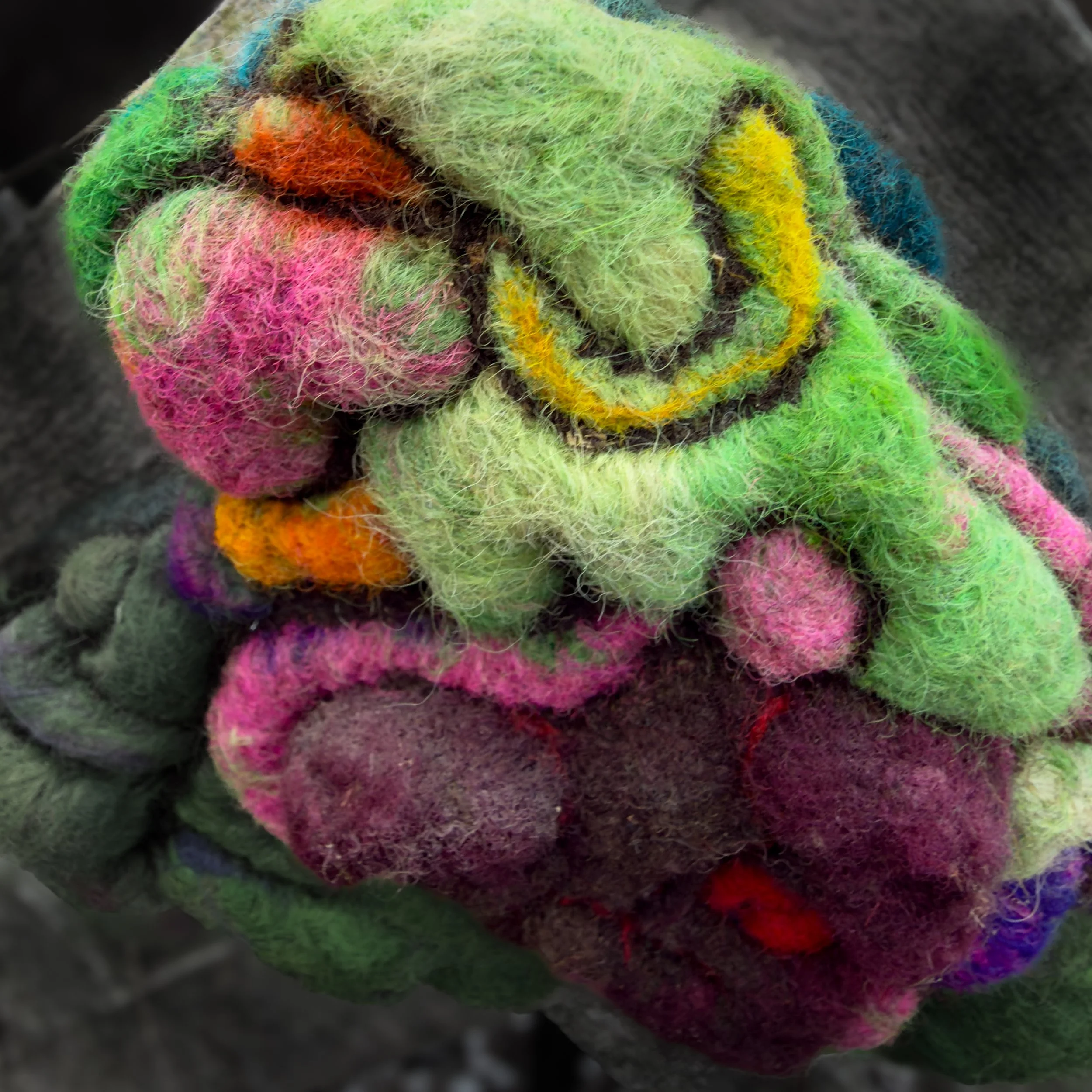 Detail of multicolored felted wool layers surrounding an inner burgundy heart