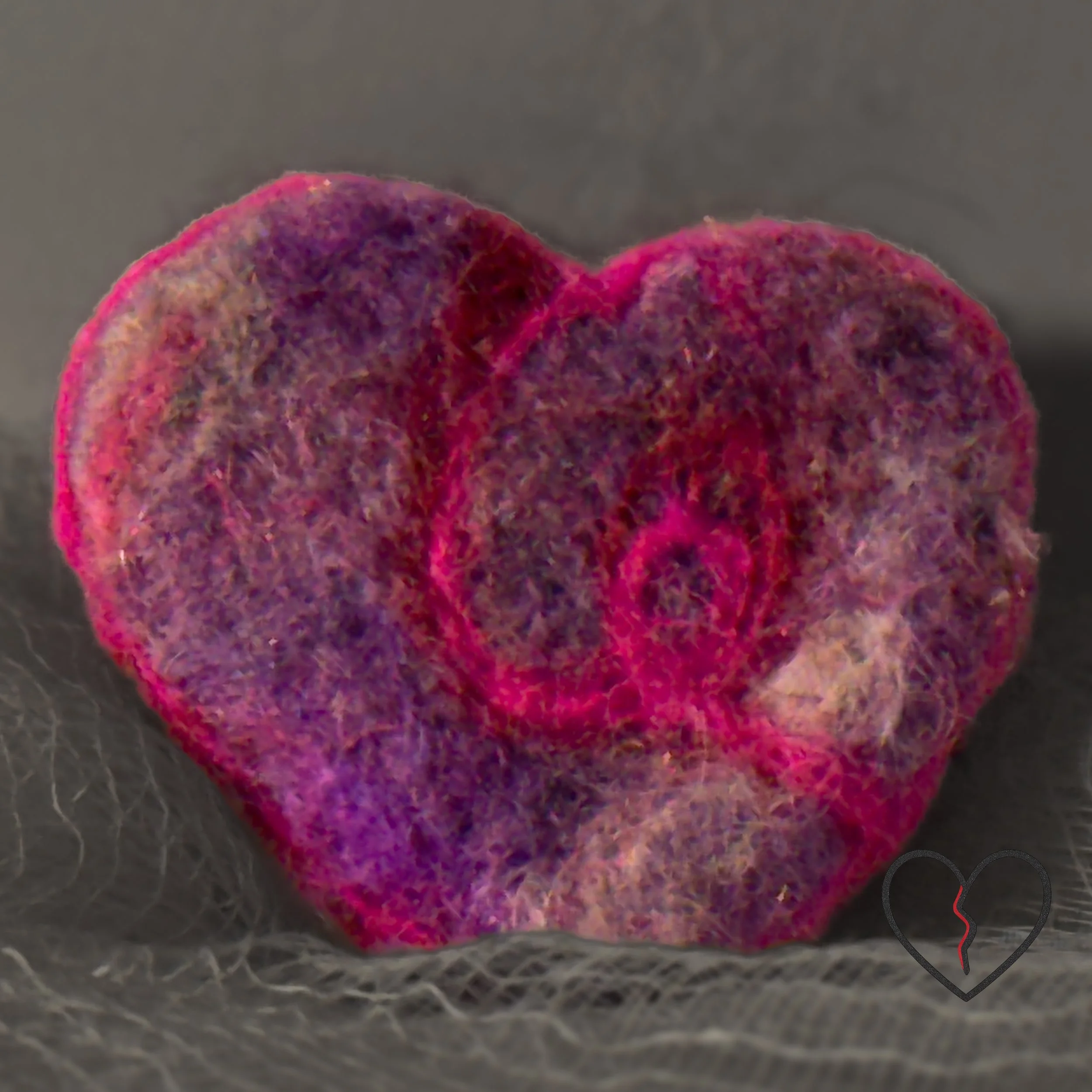 A tiny hand-felted broken heart pin made from hand-dyed purple merino wool with a soft pink wisp. Lightweight, hopeful fiber art by Kristi Yapp – Wool Alchemist.