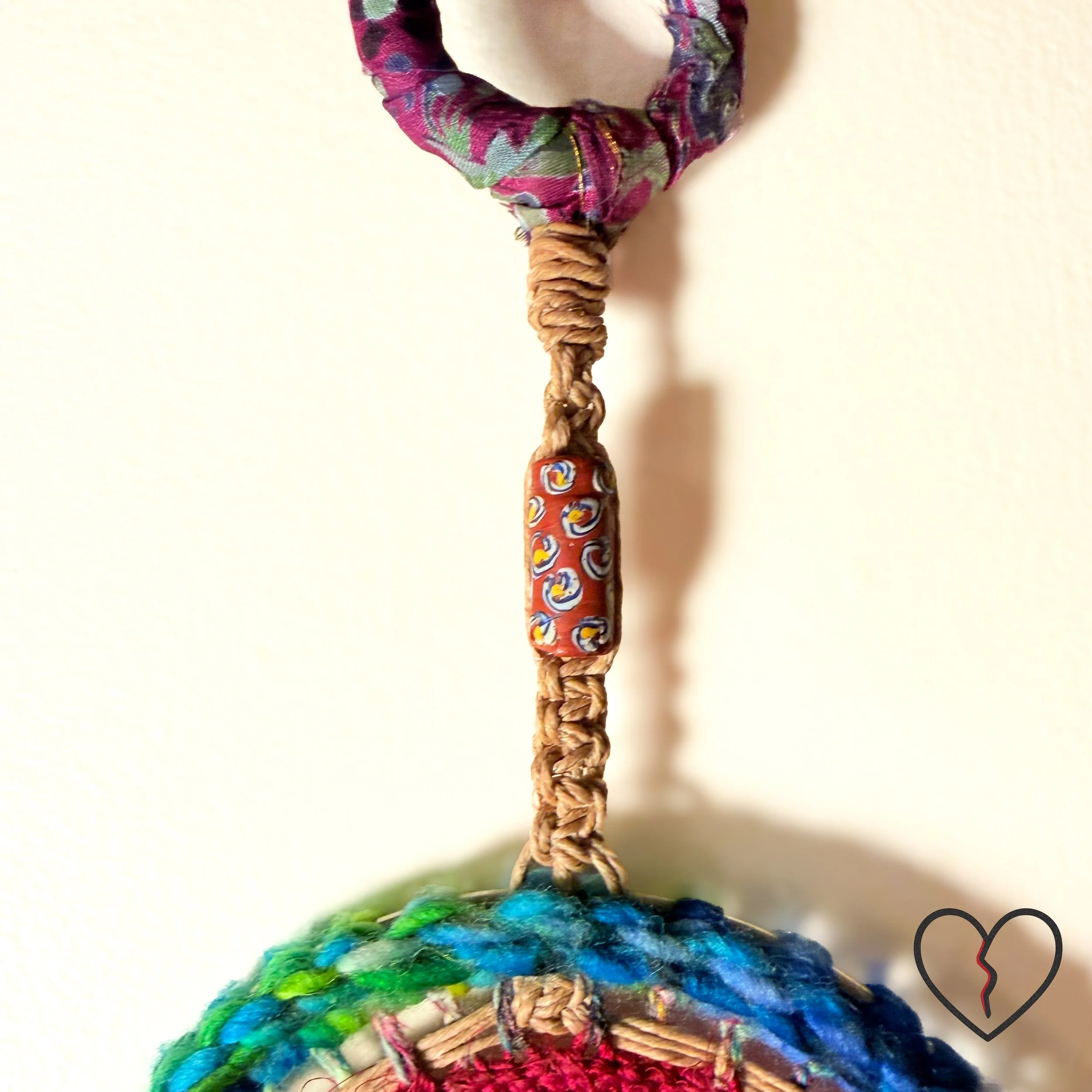 Hand crocheted wool and sari silk dreamcatcher with reclaimed prism and African trade beads representing protection, journey, and illumination. One of a kind fiber wall hanging by Kristi Yapp, 2024.