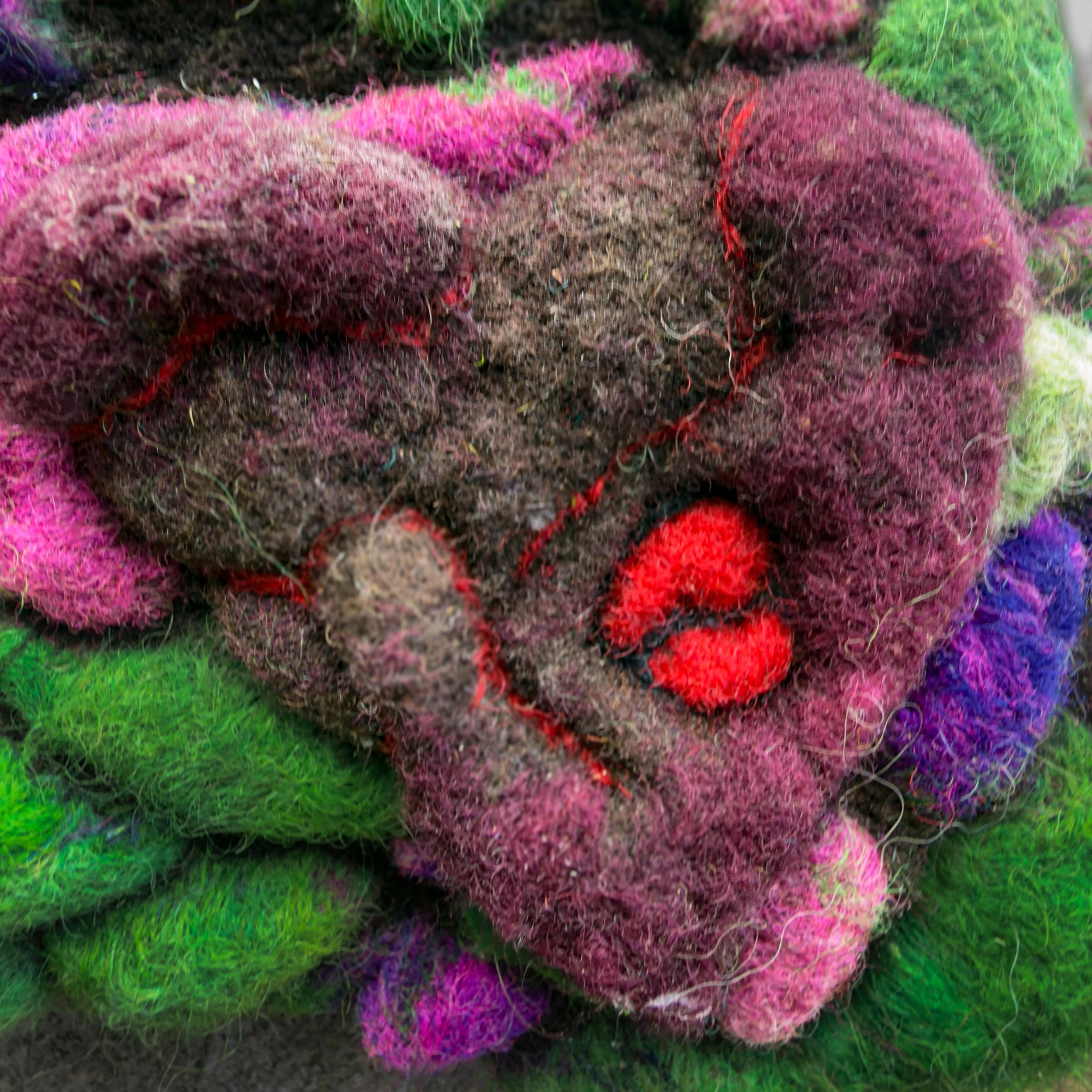 Close-up of burgundy felt heart with tiny red broken heart embedded inside