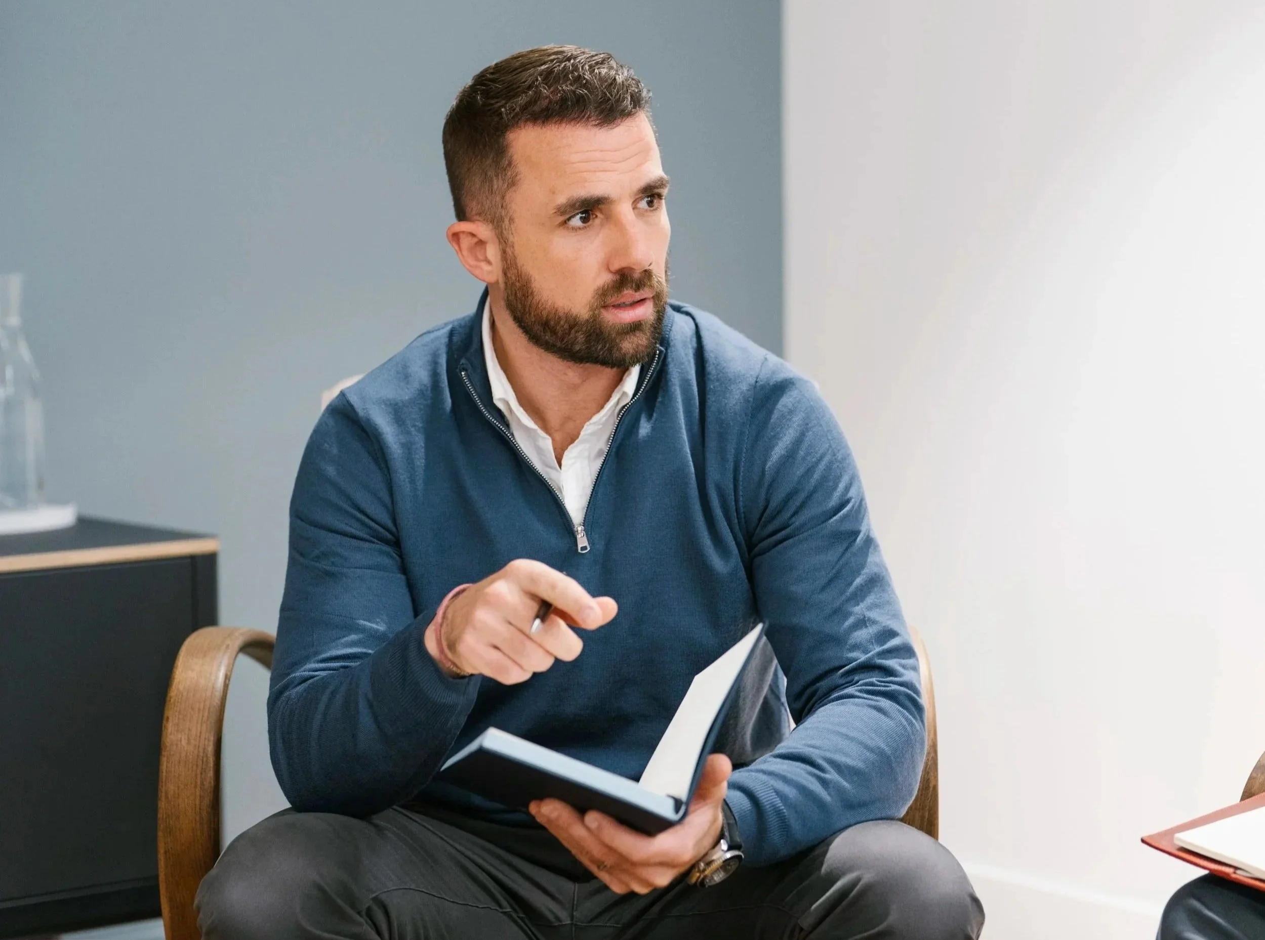 Robert sitting and speaking during a meeting in a modern office.
