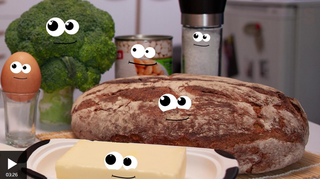 Cartoon eyes and smiles added to food items on kitchen countertop, including broccoli, egg, cheese, bread, canned beans, salt and pepper shakers, creating a playful scene.