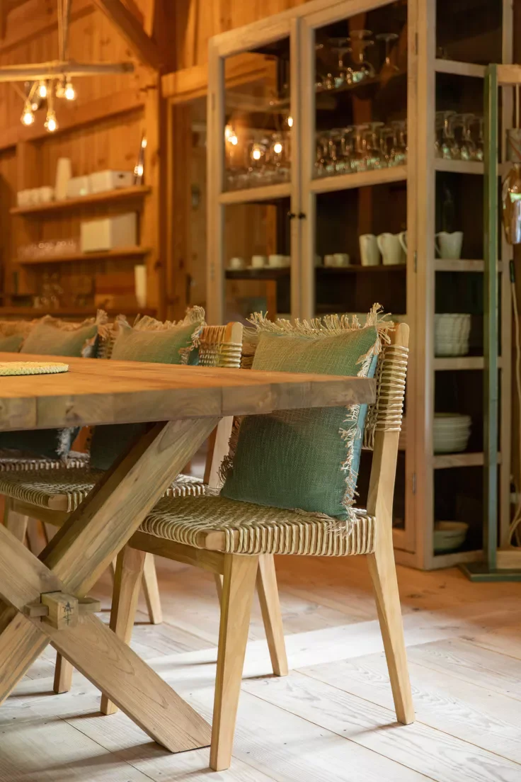 Salle à manger en bois avec une table en bois et des chaises en bois avec des coussins verts.
