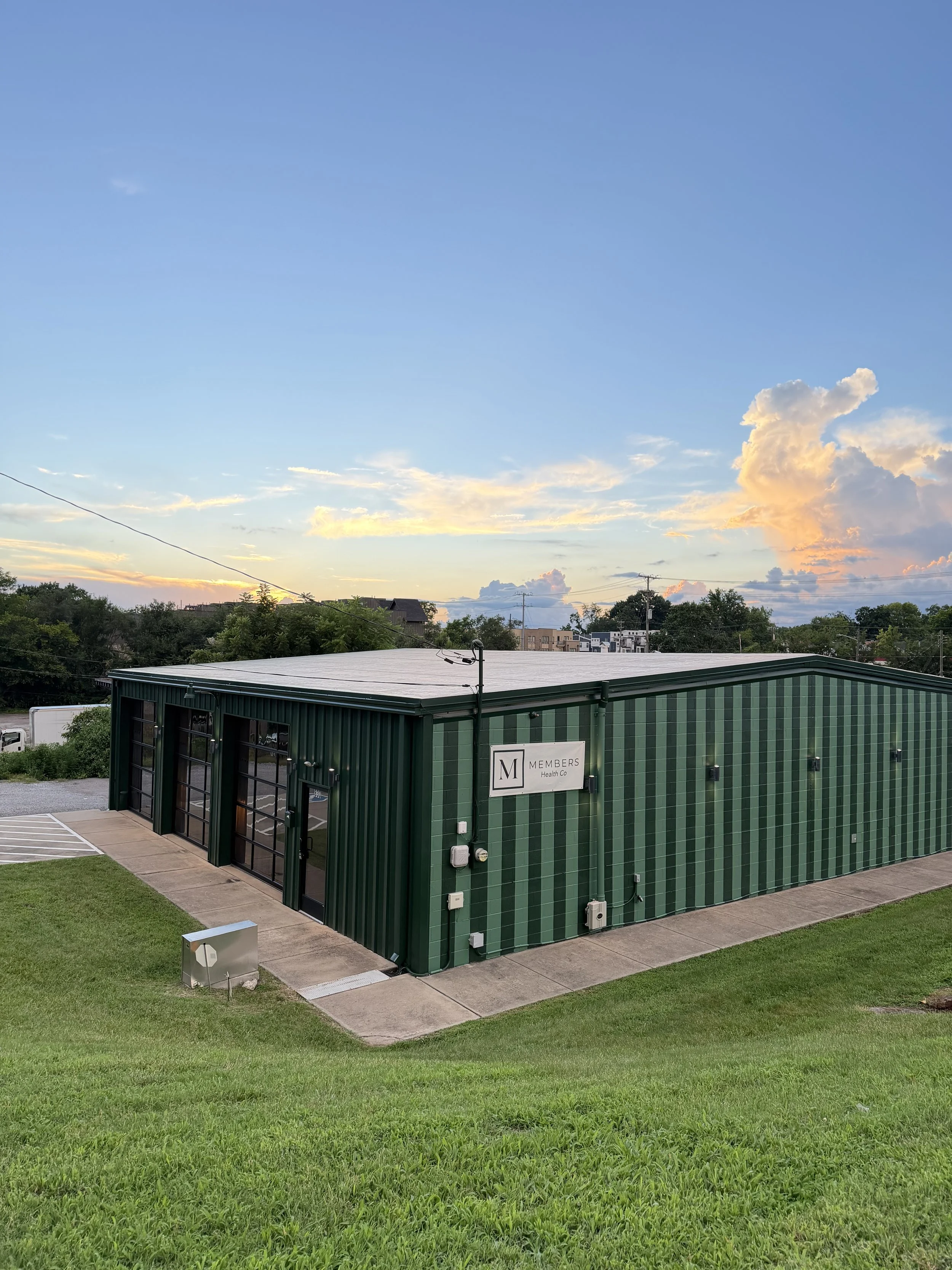 Members Health Co East Nashville clinic at 830 W McKennie Ave, a green building with glass entry doors photographed at sunset.