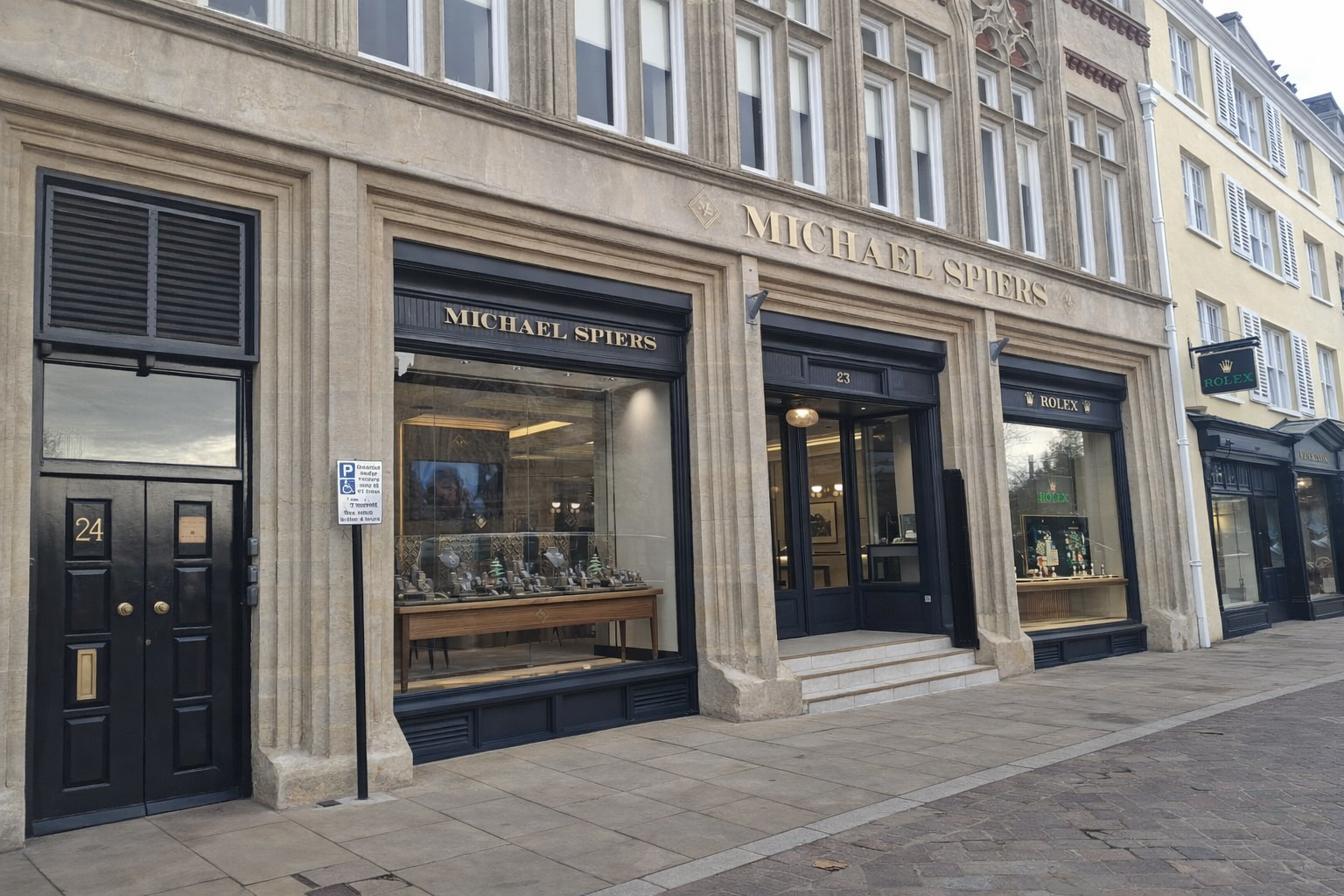  Storefront of Michael Spiers jewelry store with black window frames, a large window display, a blue door, and signage for Rolex