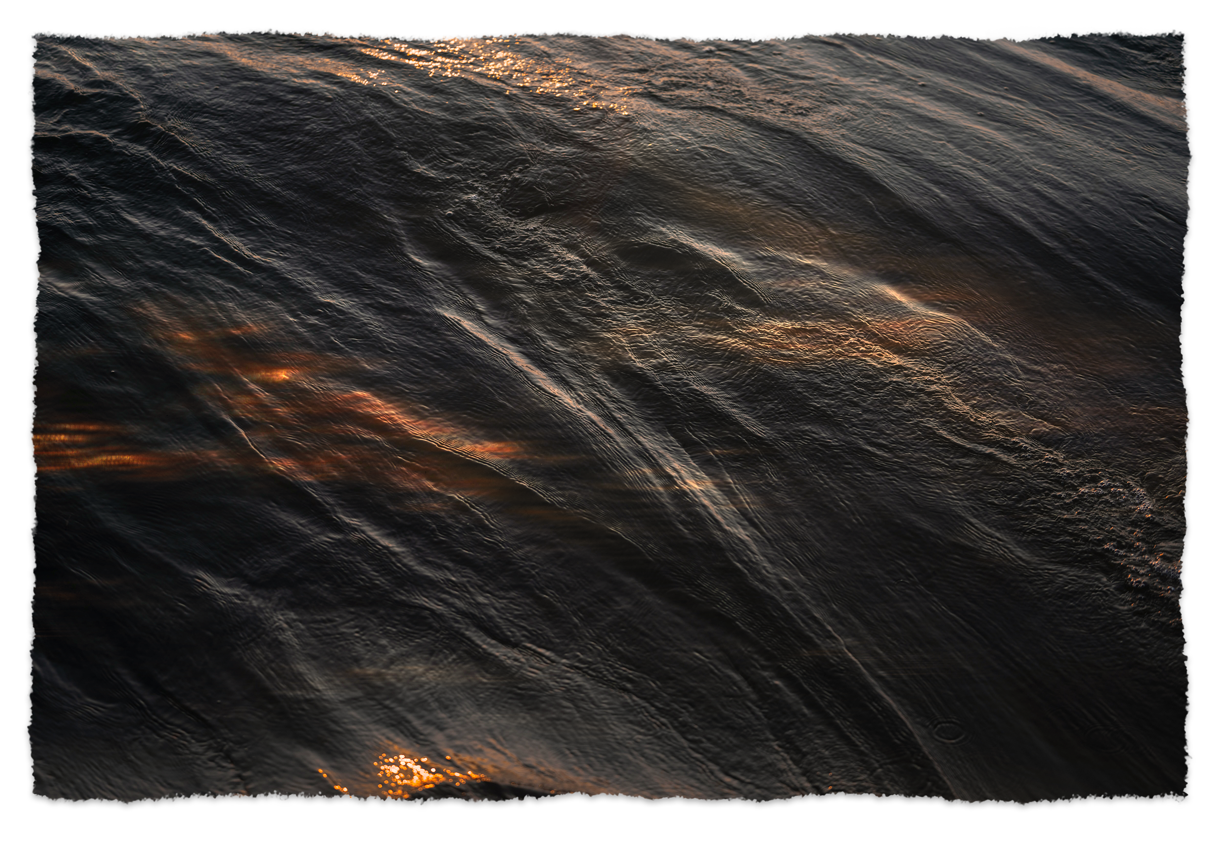 Close-up view of dark, rippling water with reflections of sunlight