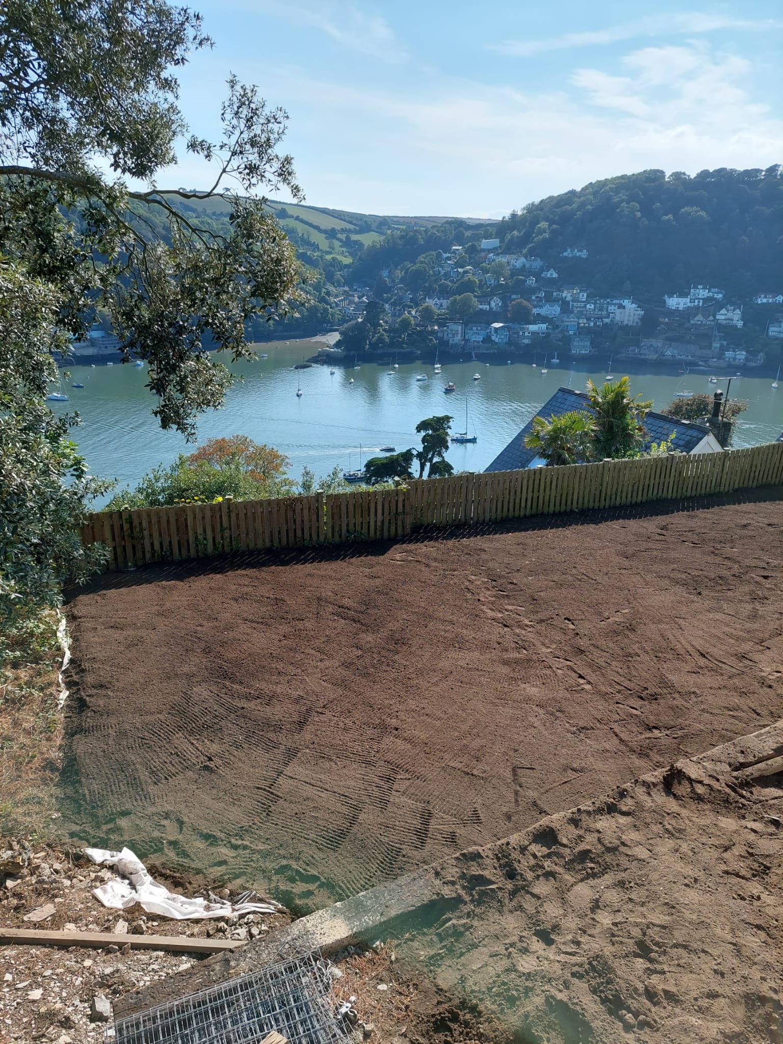 Groundwork for a landscaping job. View of the river Dart with sailboats, houses on hillside.