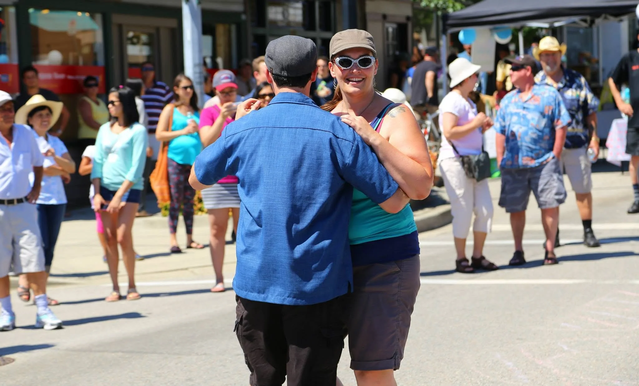 Stacy dancing with a partner, wearing sparkly sunglasses and smiling.