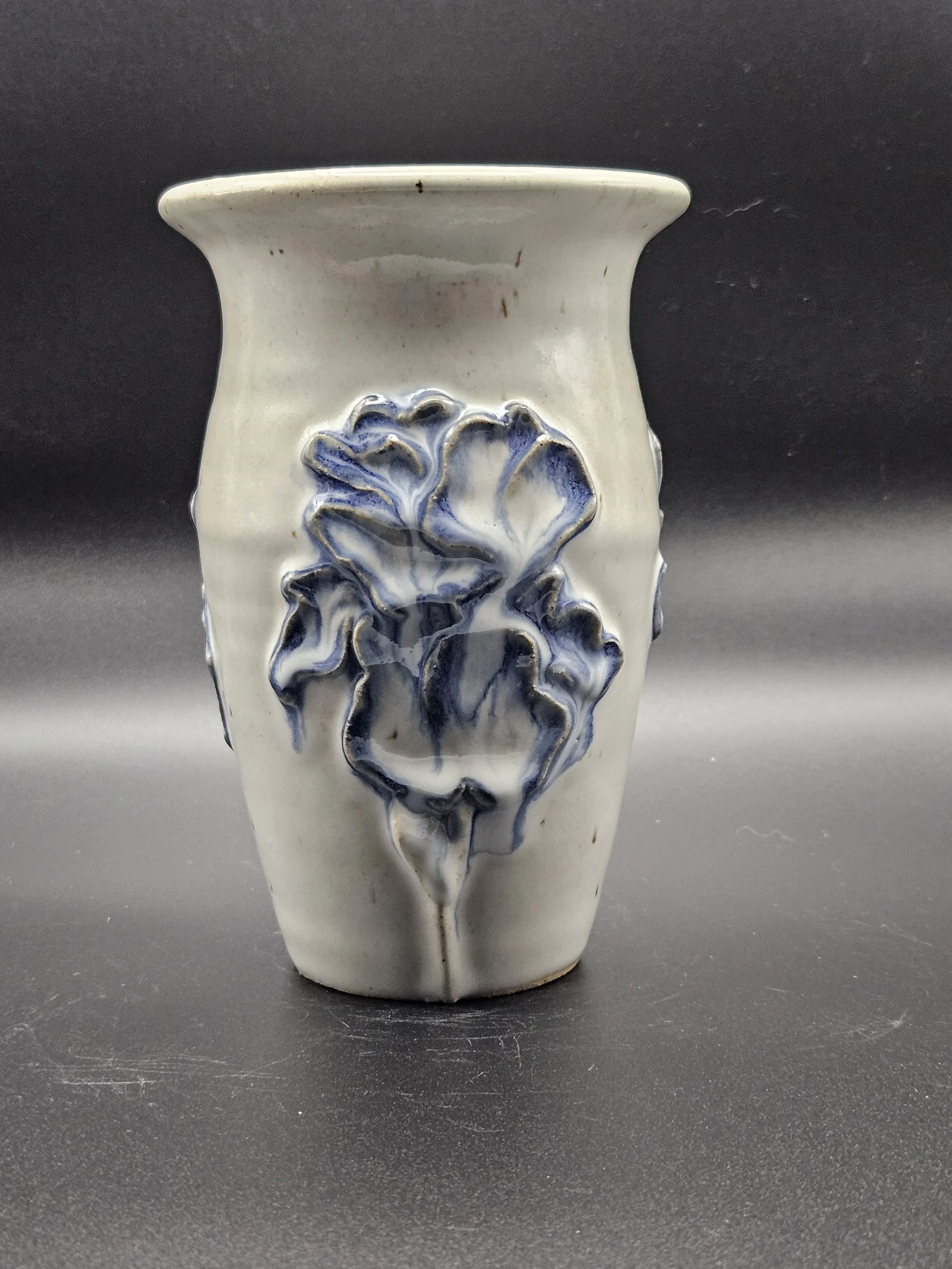 White ceramic vase with a dripping purple iris in relief.