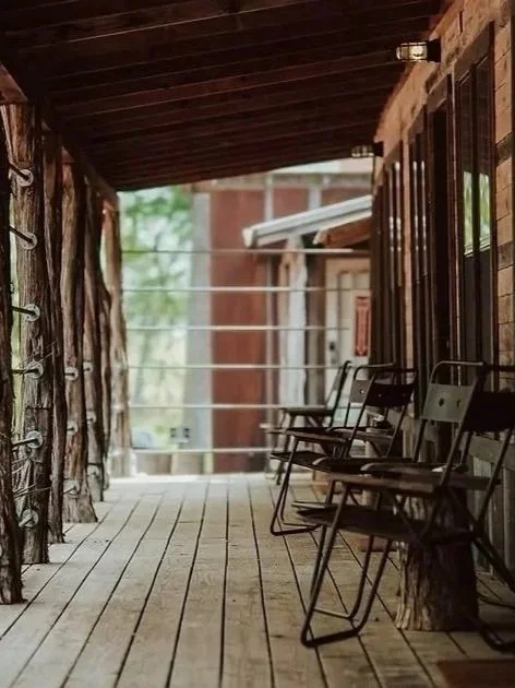 Porch with wooden floor and chairs outside a rustic building