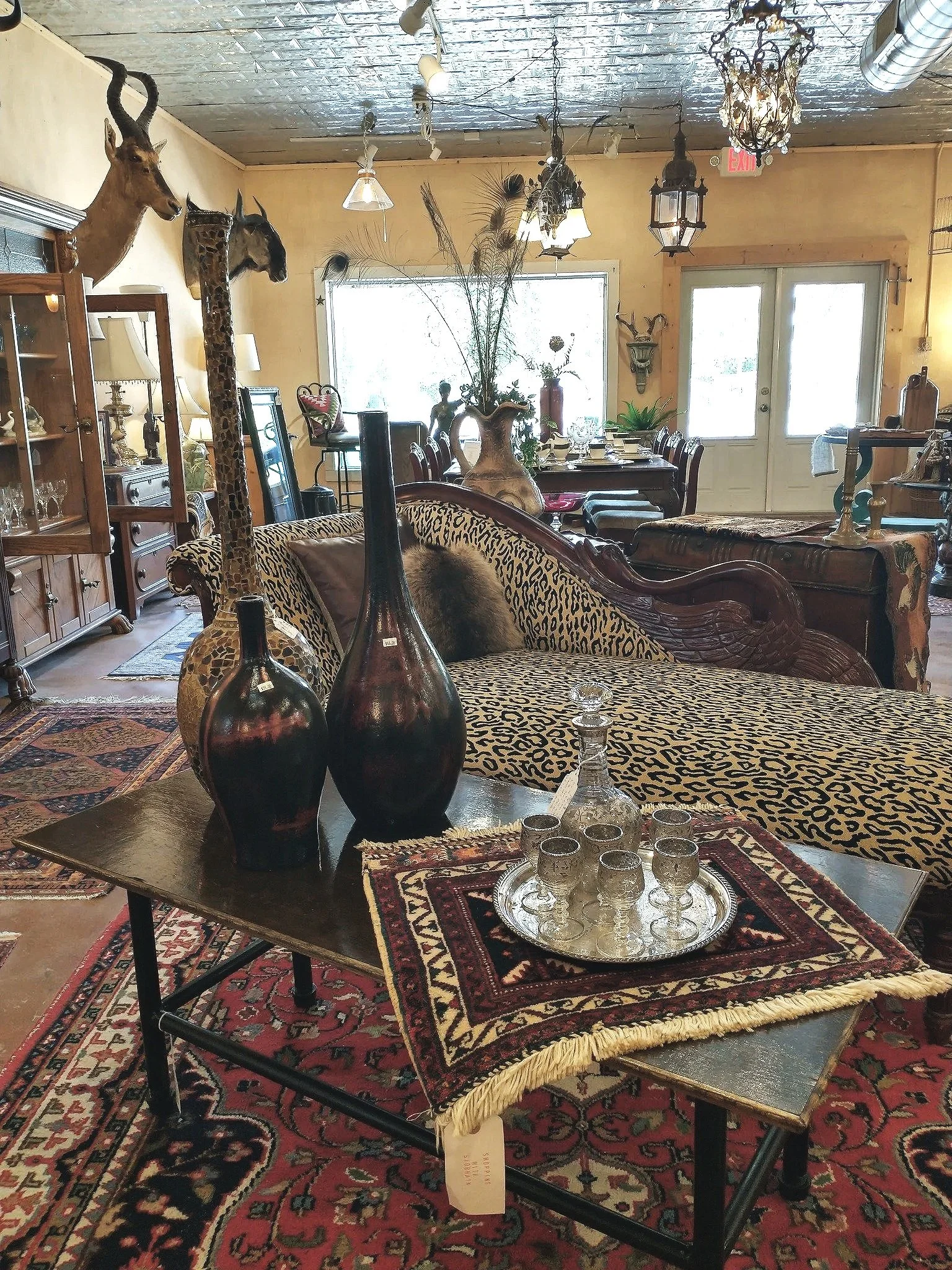 Interior of an eclectic living room with mounted animal heads, decorative vases, and vintage furniture.