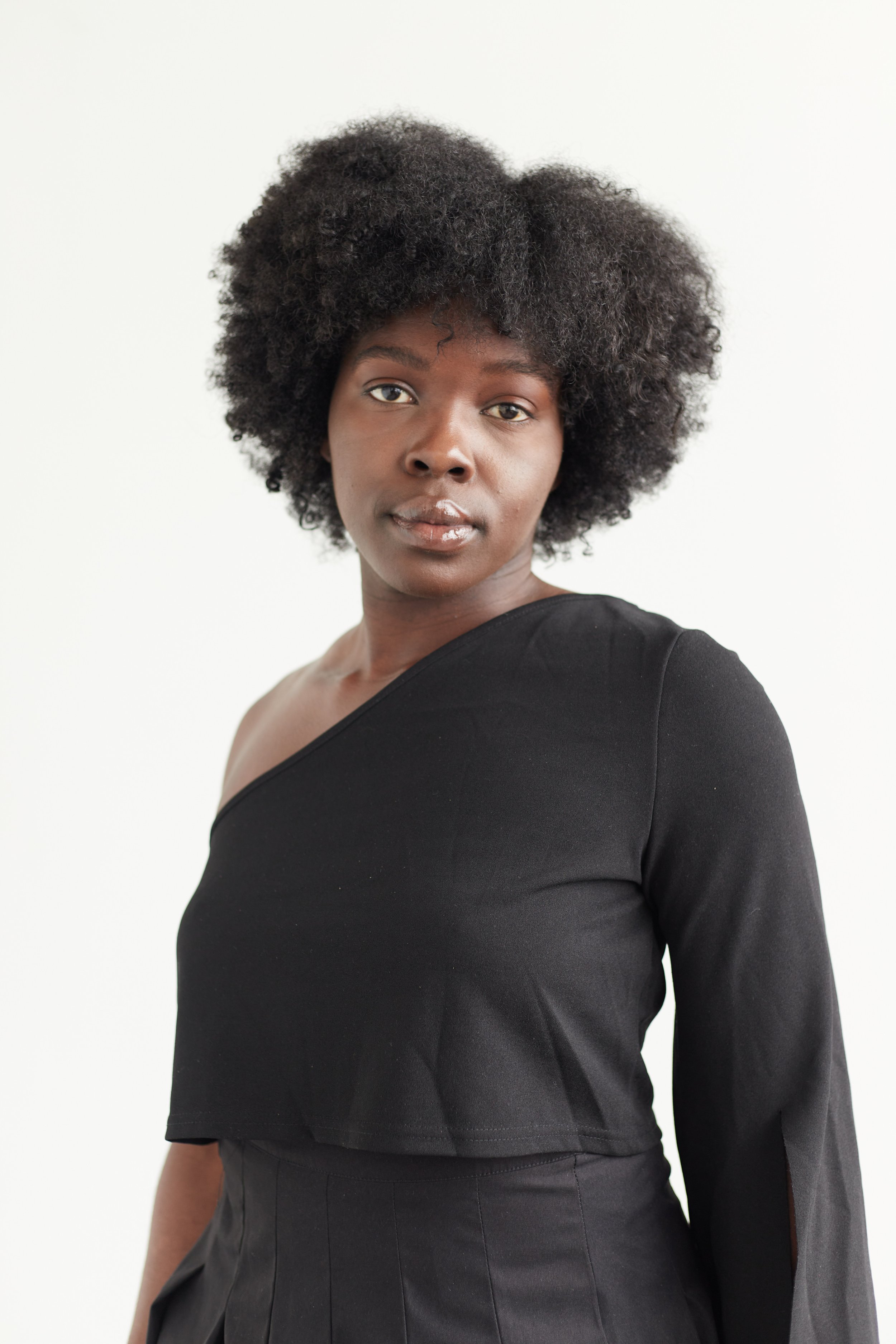 Portrait of a woman with short curly hair wearing a black top against a white background.