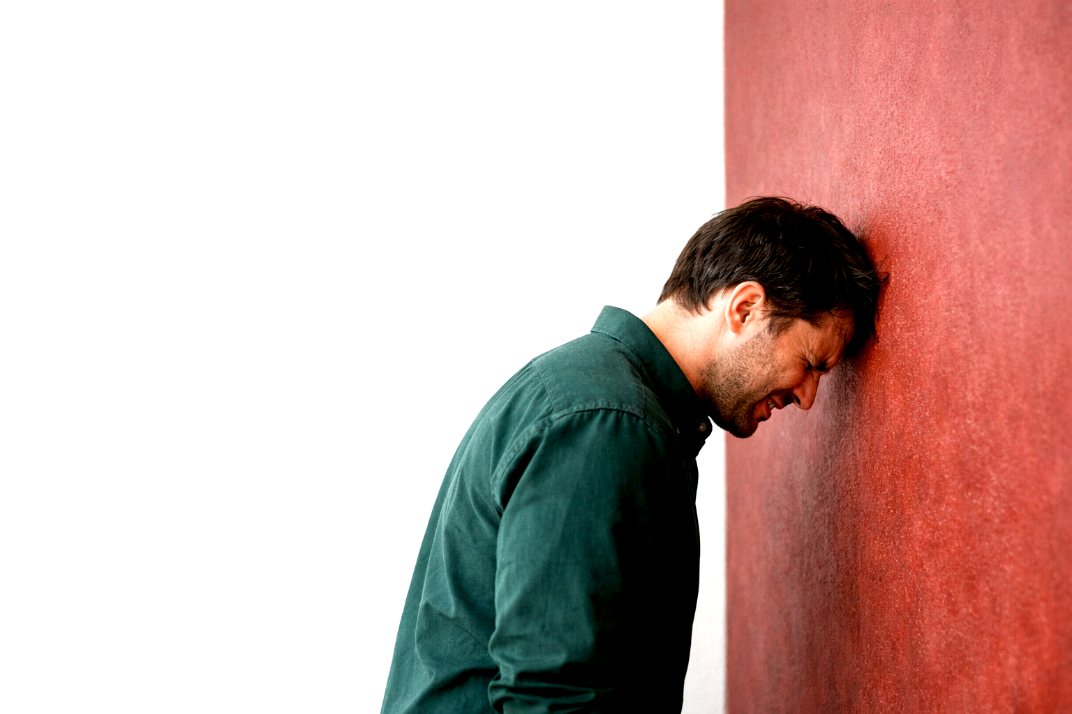 Man banging his head against a brick wall
