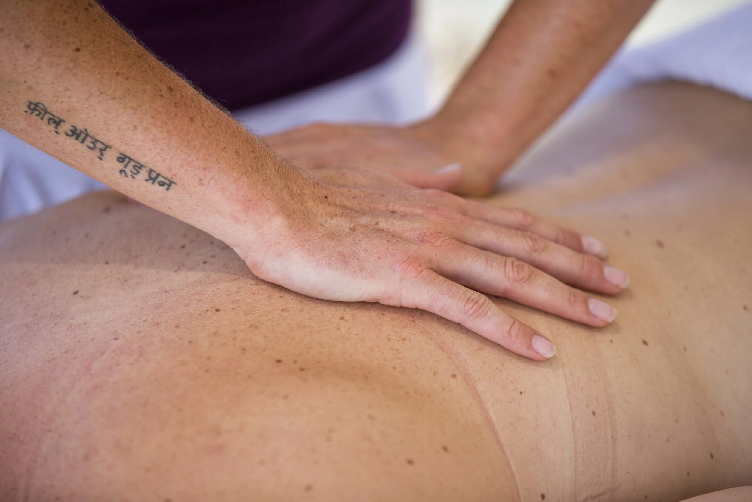 Close-up of a person's hand performing a massage on another person's back in a massage therapy session.