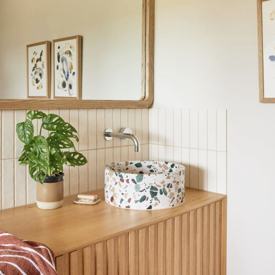Clean modern bathroom vanity with terrazzo vessel sink, wood cabinetry, and decorative plant, showcasing professional cleaning services in Scottsdale Arizona