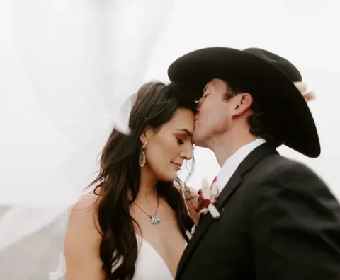 A bride and groom sharing a tender moment, with their foreheads touching, during their wedding ceremony.