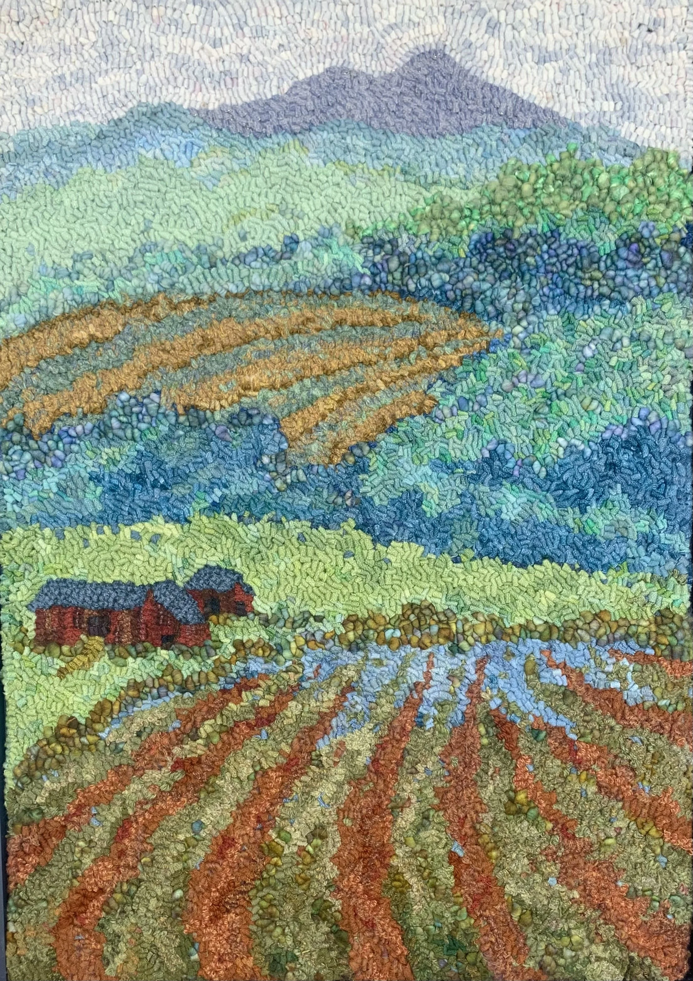 Mosaic artwork depicting a scenic landscape of rolling hills, cultivated fields, a farmhouse, a river, and distant mountains.