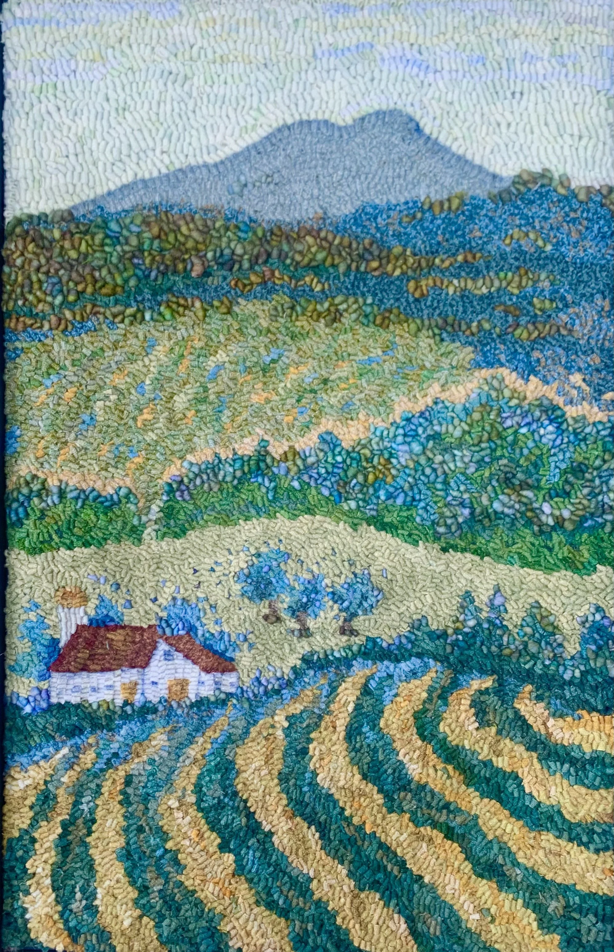 A colorful landscape mosaic depicting rolling hills, a house with a red roof, trees, and a mountain in the background.