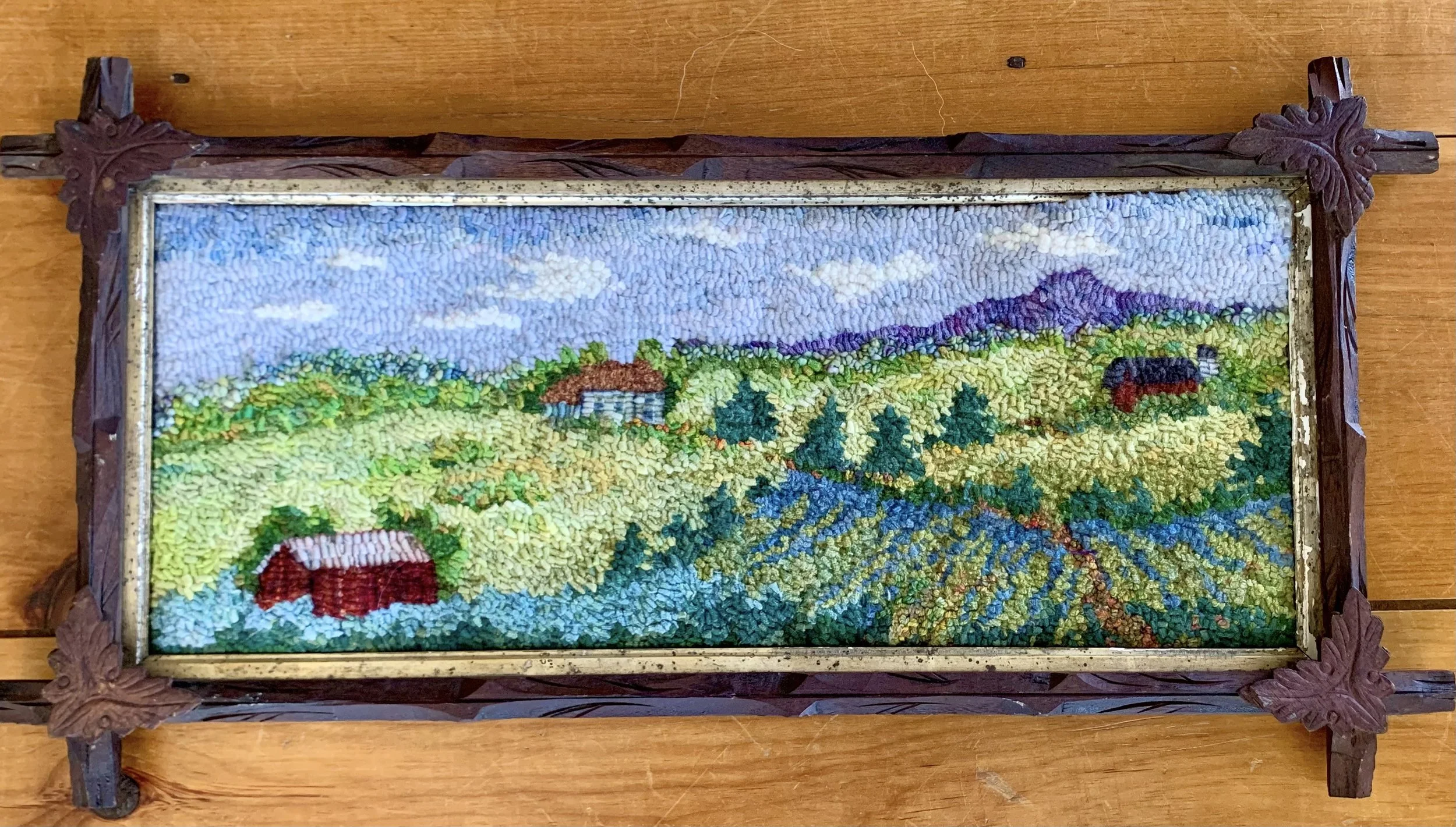 Colorful rural landscape with houses, trees, fields, and mountains under a partly cloudy sky.