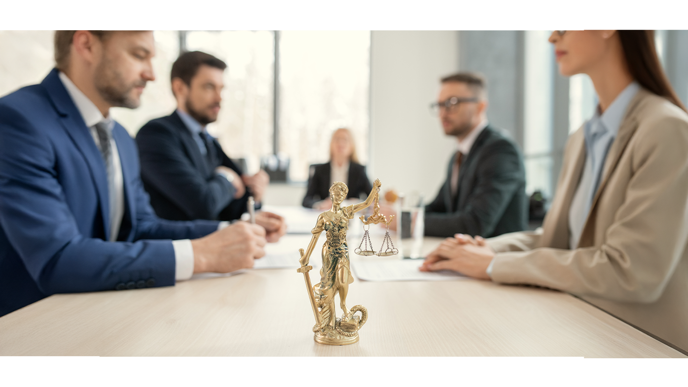 Reunión de abogados en una sala con una estatua de la diosa de la justicia en primer plano.