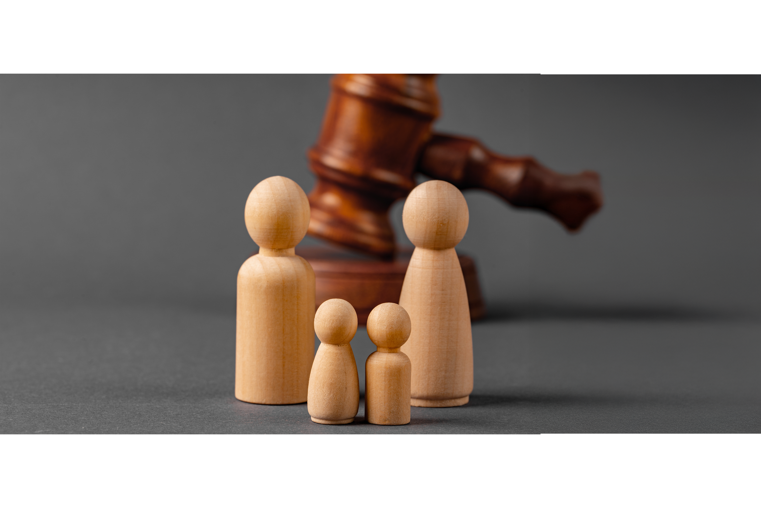 Figuritas de madera de una familia con un martillo de juez en el fondo.