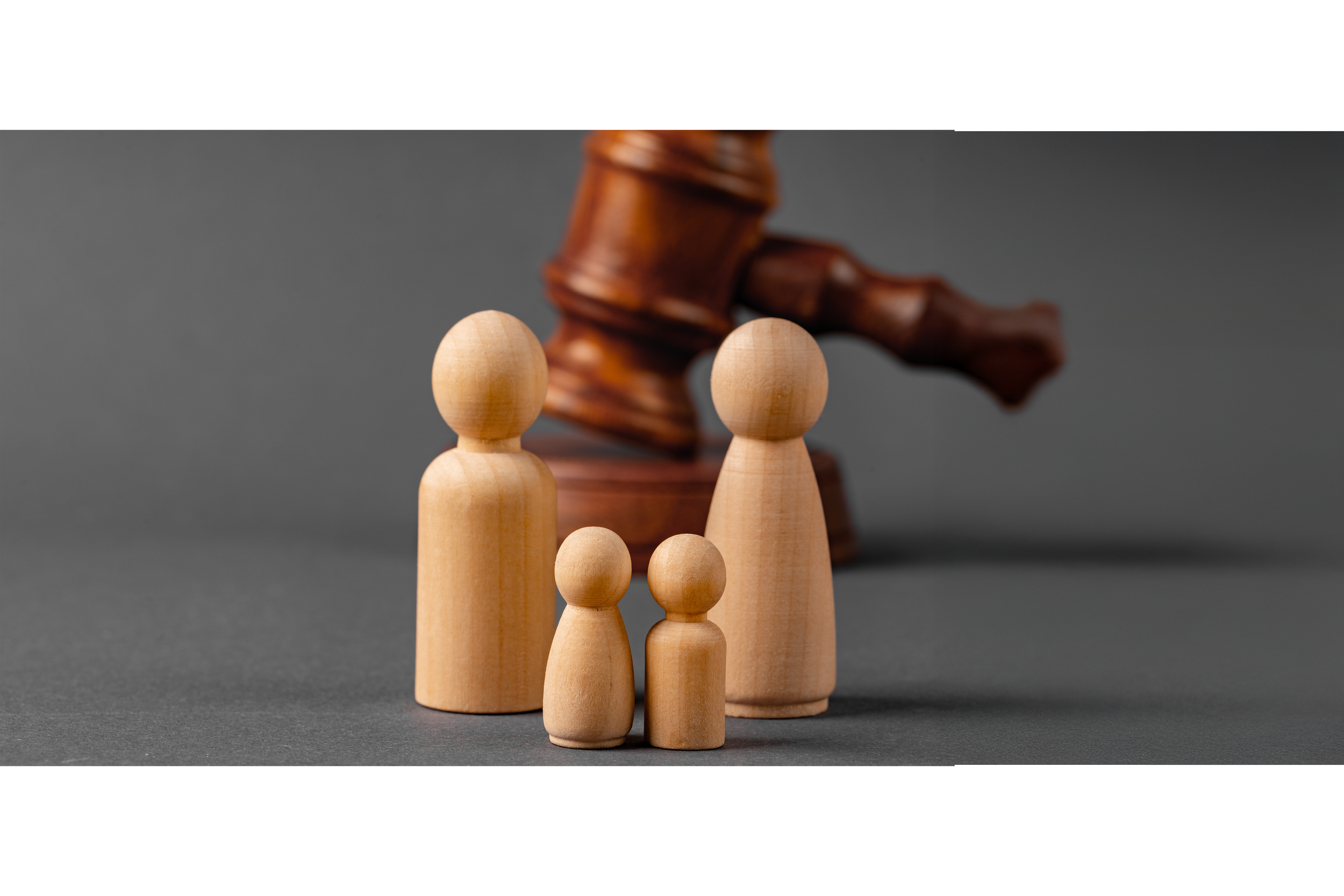 Figuras de madera de diferentes tamaños con un martillo de juez en el fondo sobre un fondo gris.