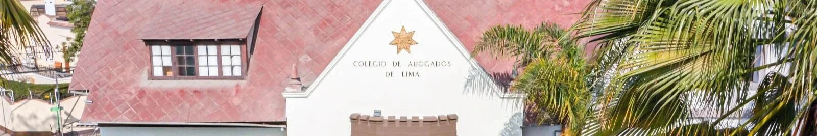 Vista panorámica del Colegio de Abogados de Lima con techo de tejas rojas y palmeras a los lados.