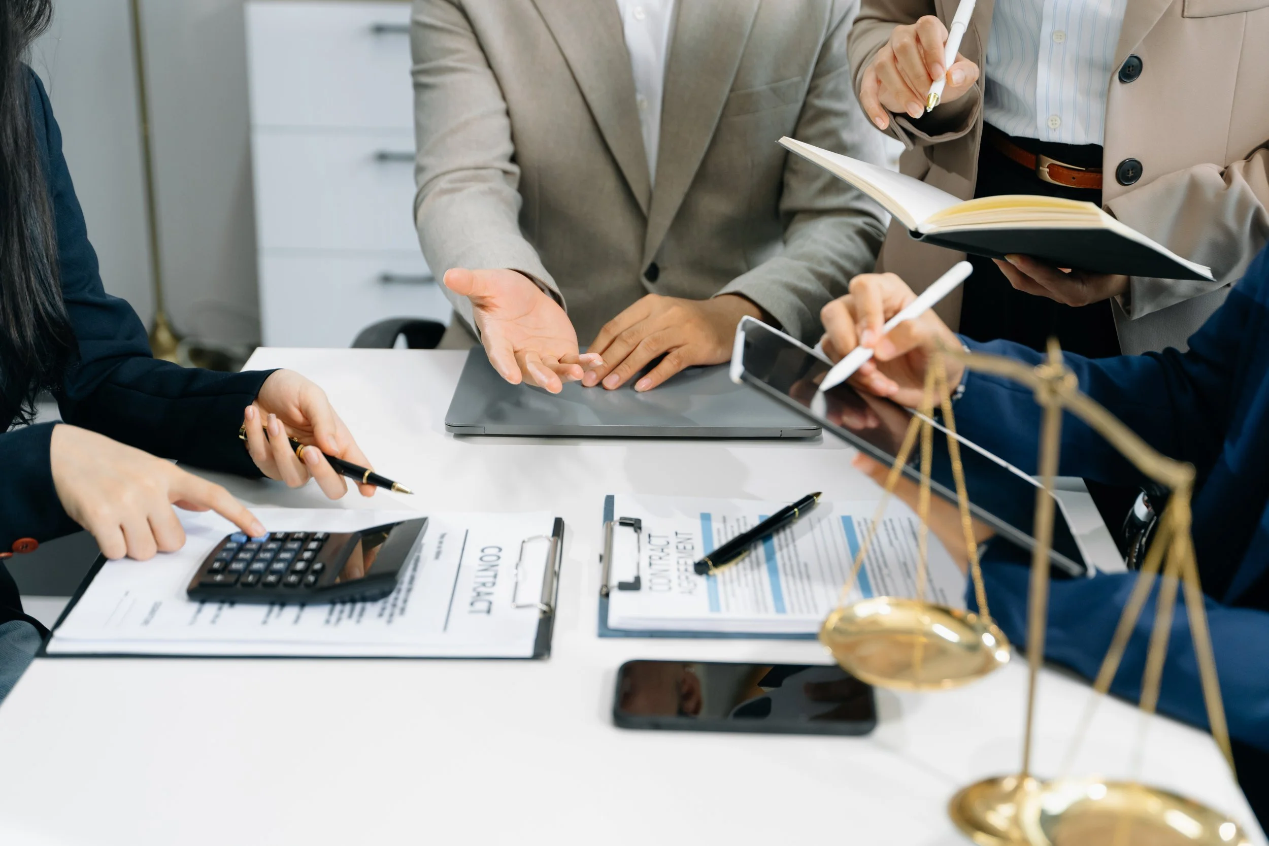Personas en una reunión de trabajo discutiendo contratos y documentos legales en una oficina.