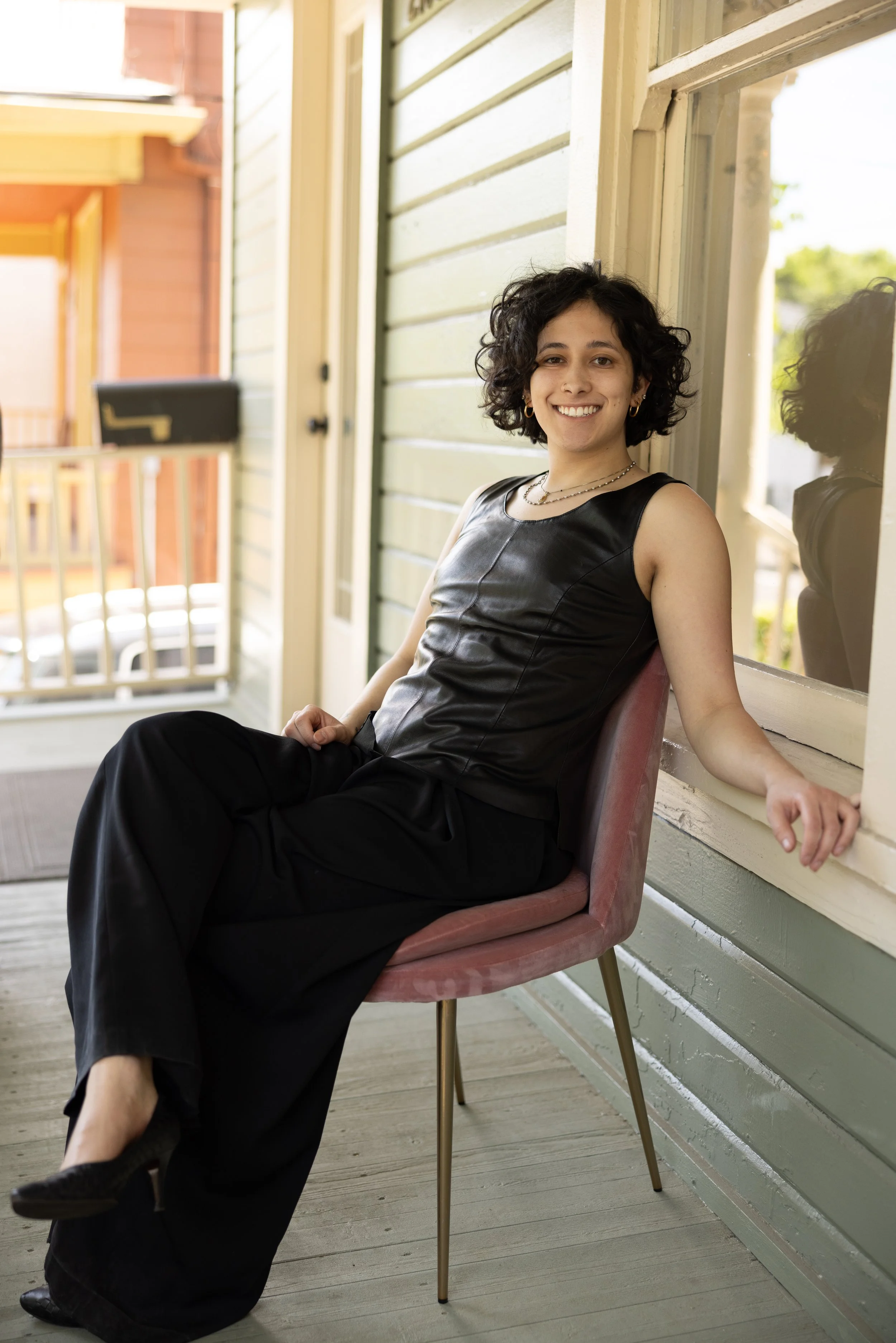 Kai Leyva, curl specialist at Gilded Fox, smiling against a brick wall, Portland Oregon curly hair salon