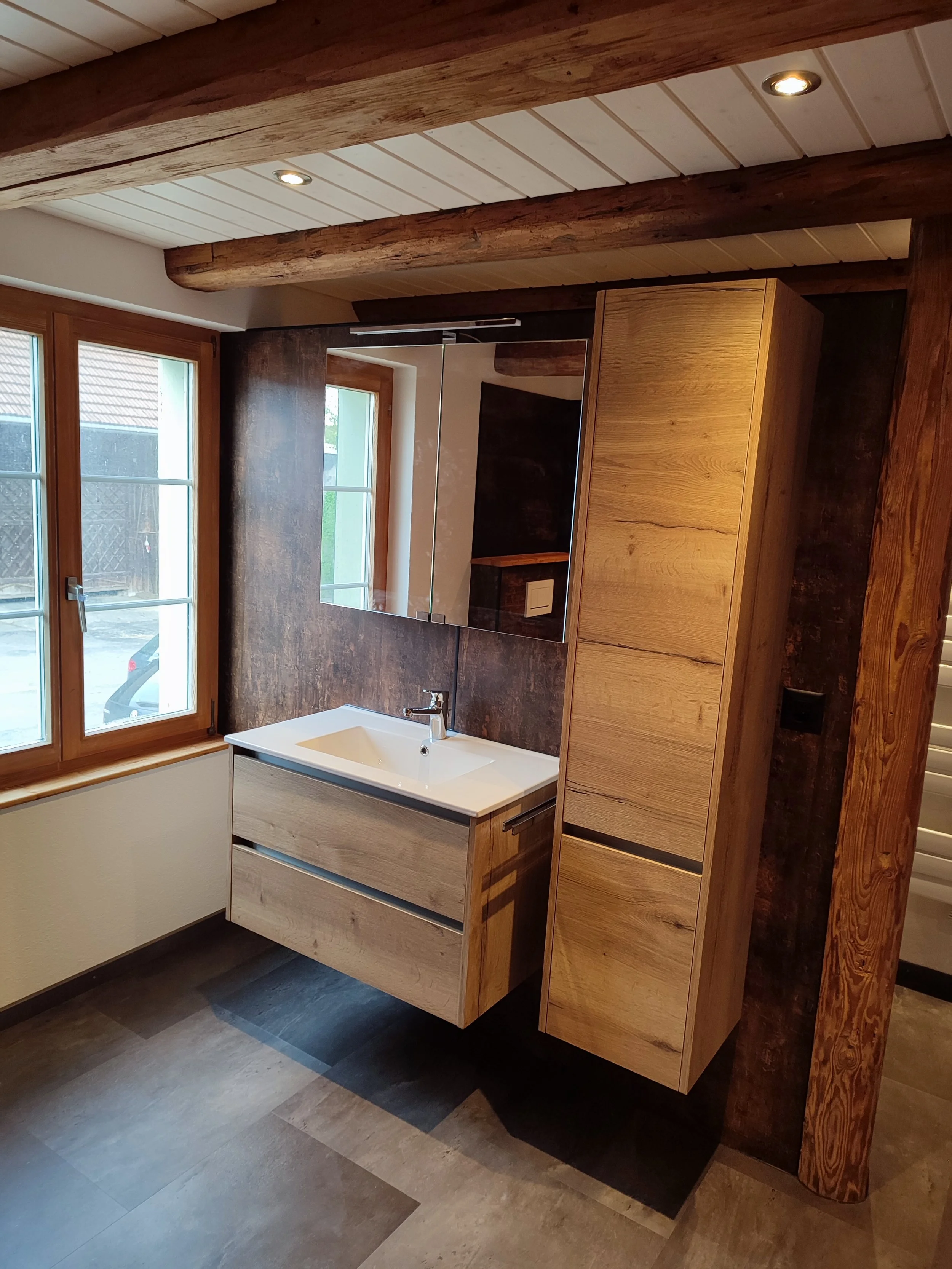Moderne Badezimmer mit Holzregal und Spiegel, Waschbecken, Fenster, dunkle Wandpaneele und Holzdecke.
