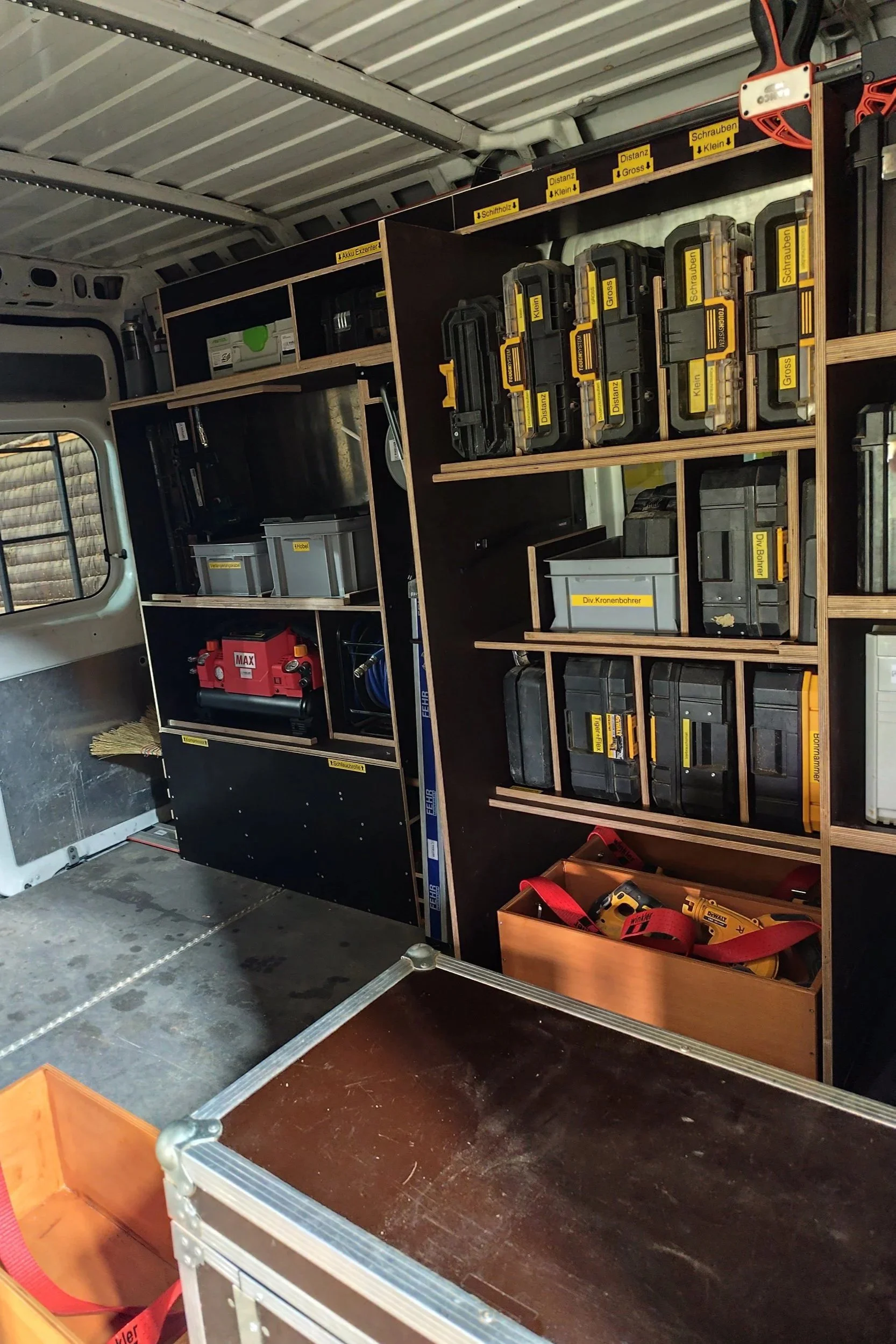Werkzeugschrank mit verschiedenen Werkzeugkoffern und -boxen, in einem Fahrzeug.