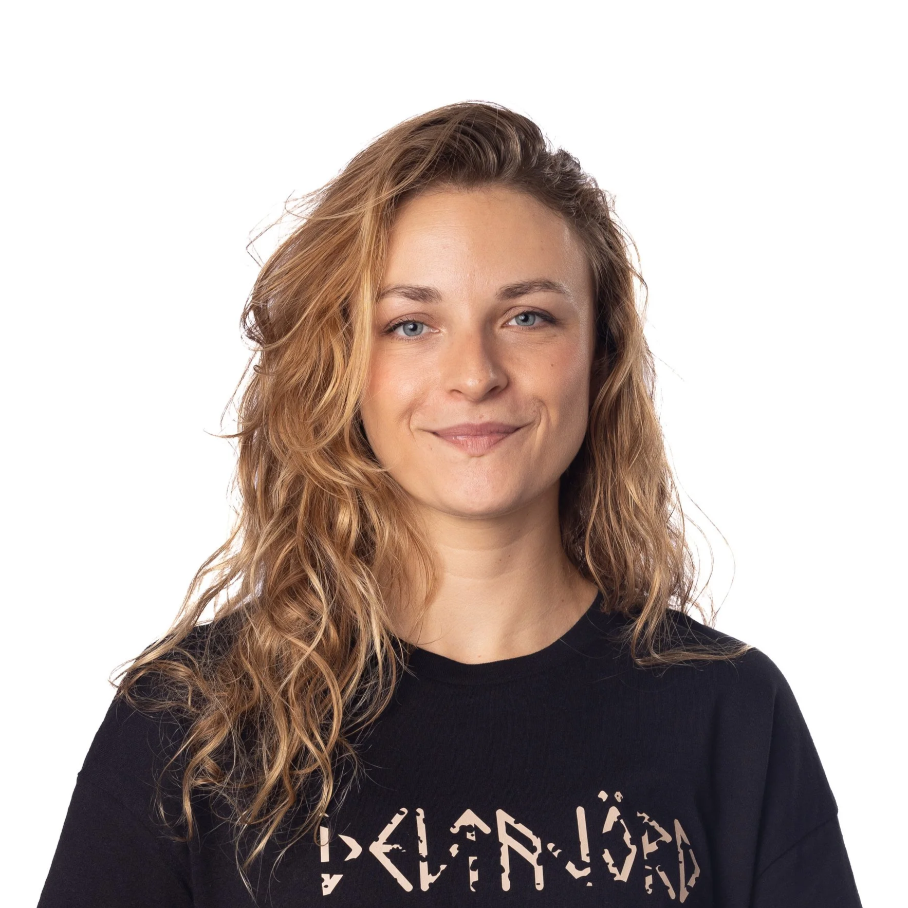 Alexie Bonaventure, créatrice de Bonaventure Events : A woman with wavy blonde hair smiling, wearing a black t-shirt with a partially visible graphic design, on a white background.