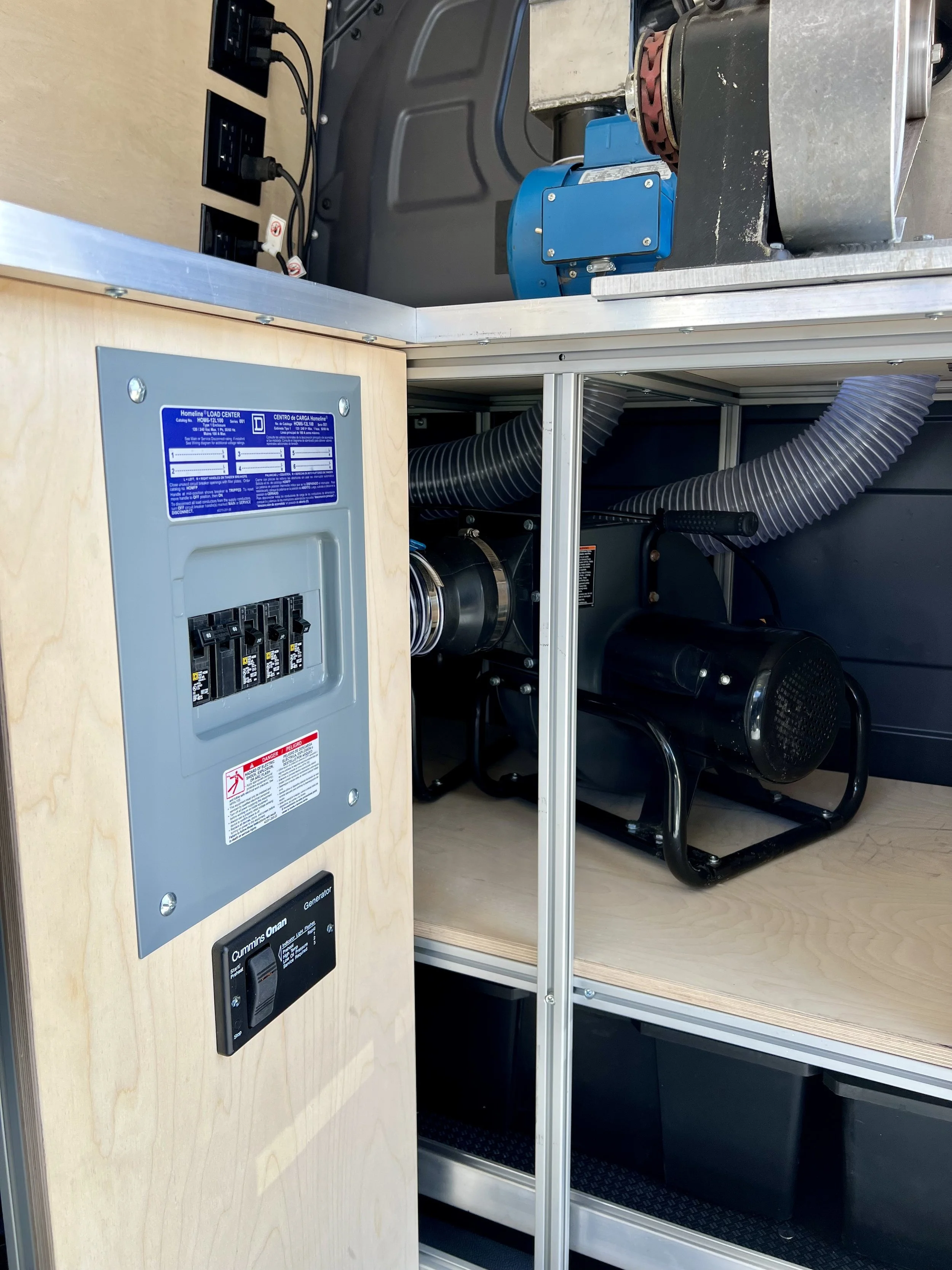 Electrical control panel inside a machine or equipment cabinet with circuit breakers, a generator, and various ducts and tubes.