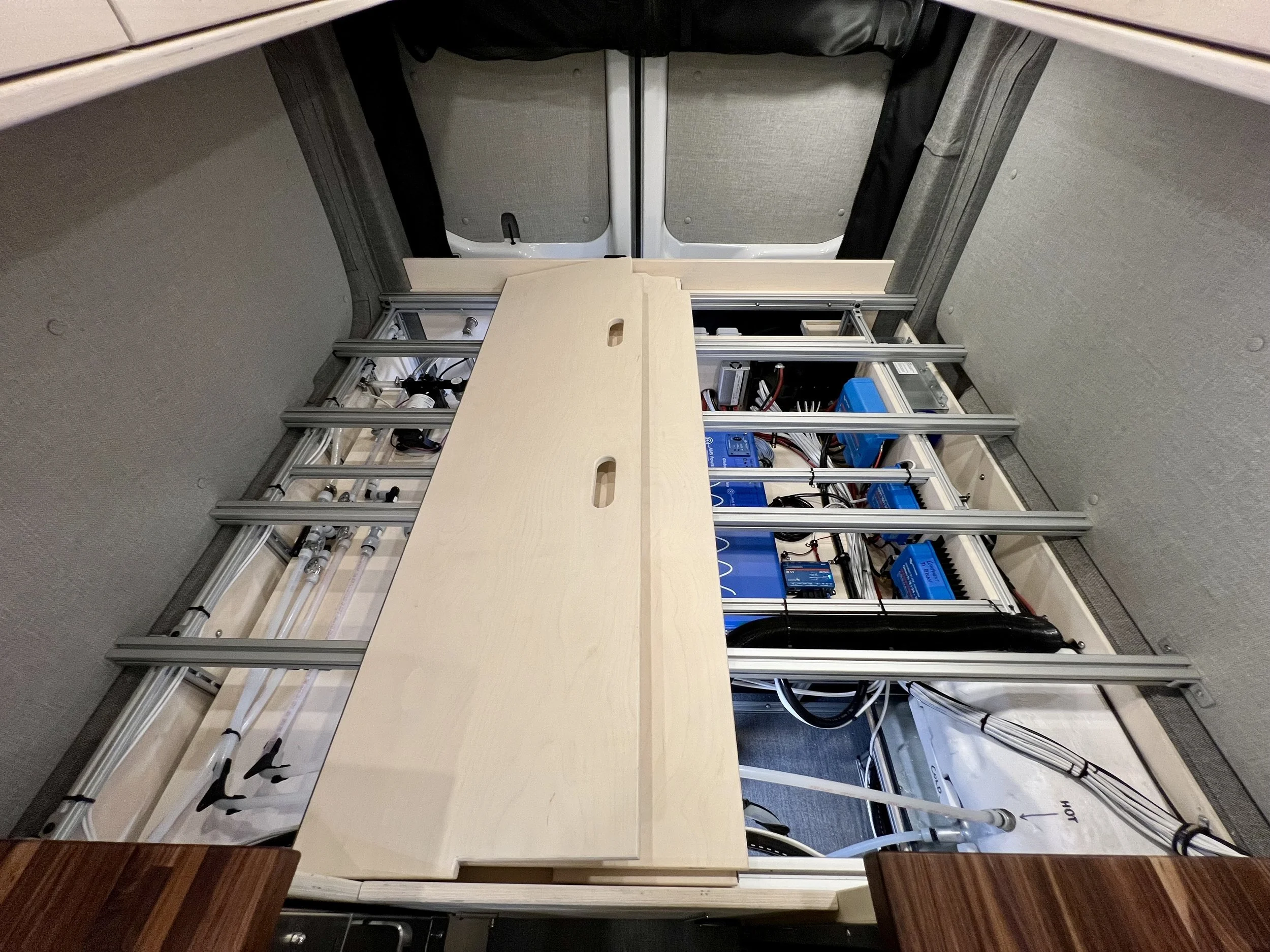 Open cabinet showing internal mechanical and electronic components, including blue batteries, wiring, and metal framing.