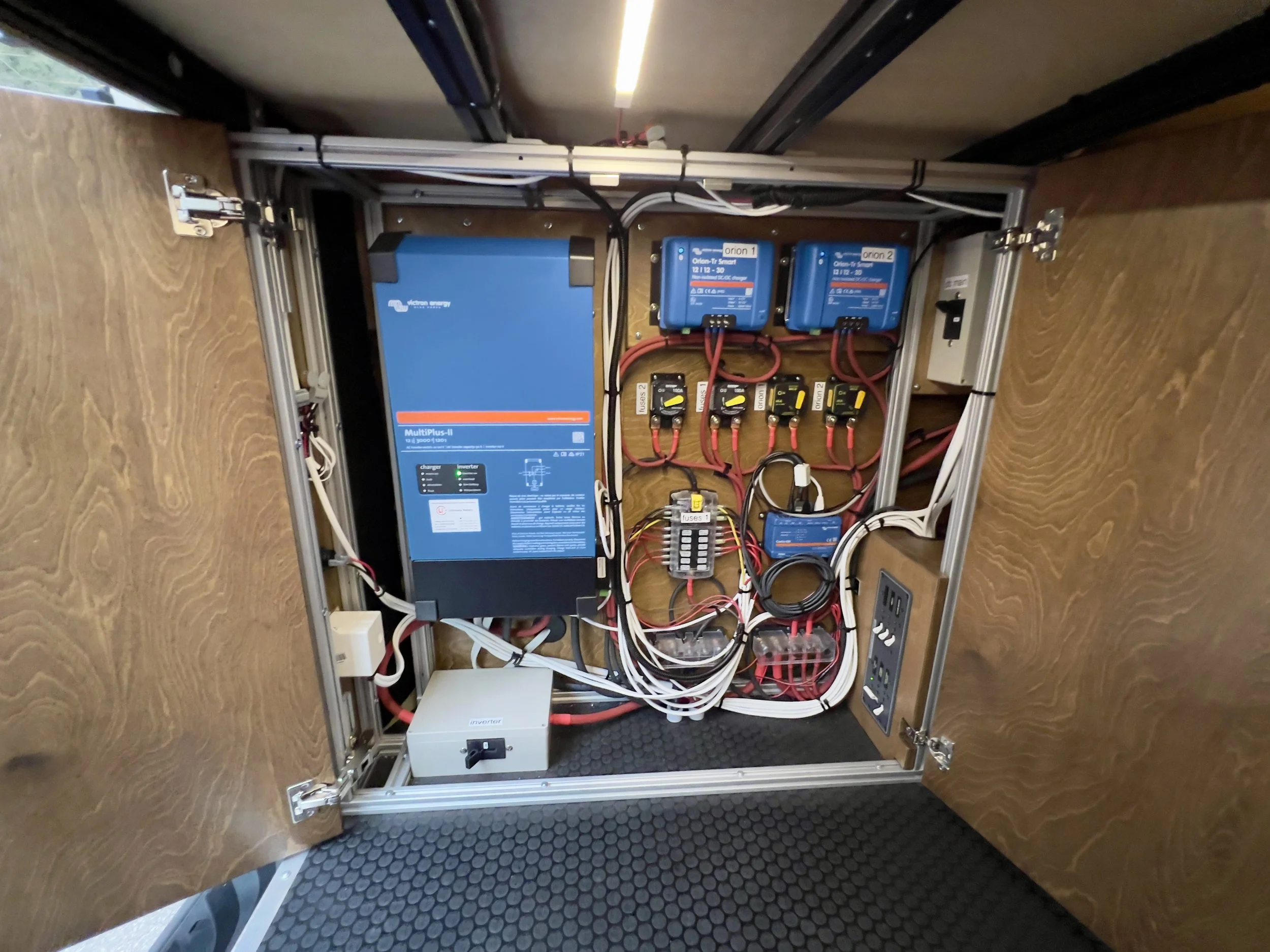 Interior of a portable electrical control box with blue and black electronic components, wiring, and switches mounted inside a wooden frame.