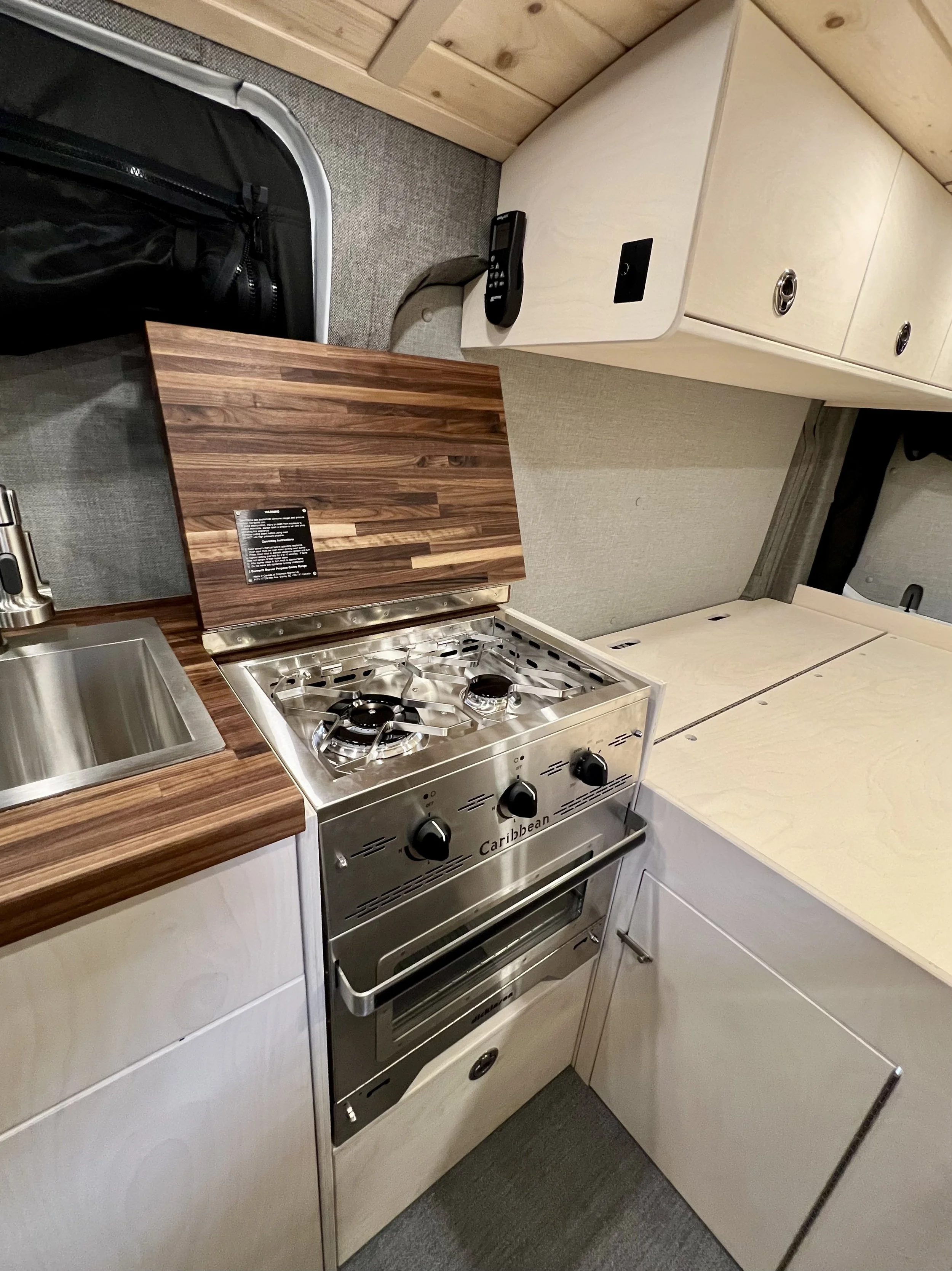Compact kitchen with a two-burner stove, sink, storage cabinets, and a black telephone on the countertop.