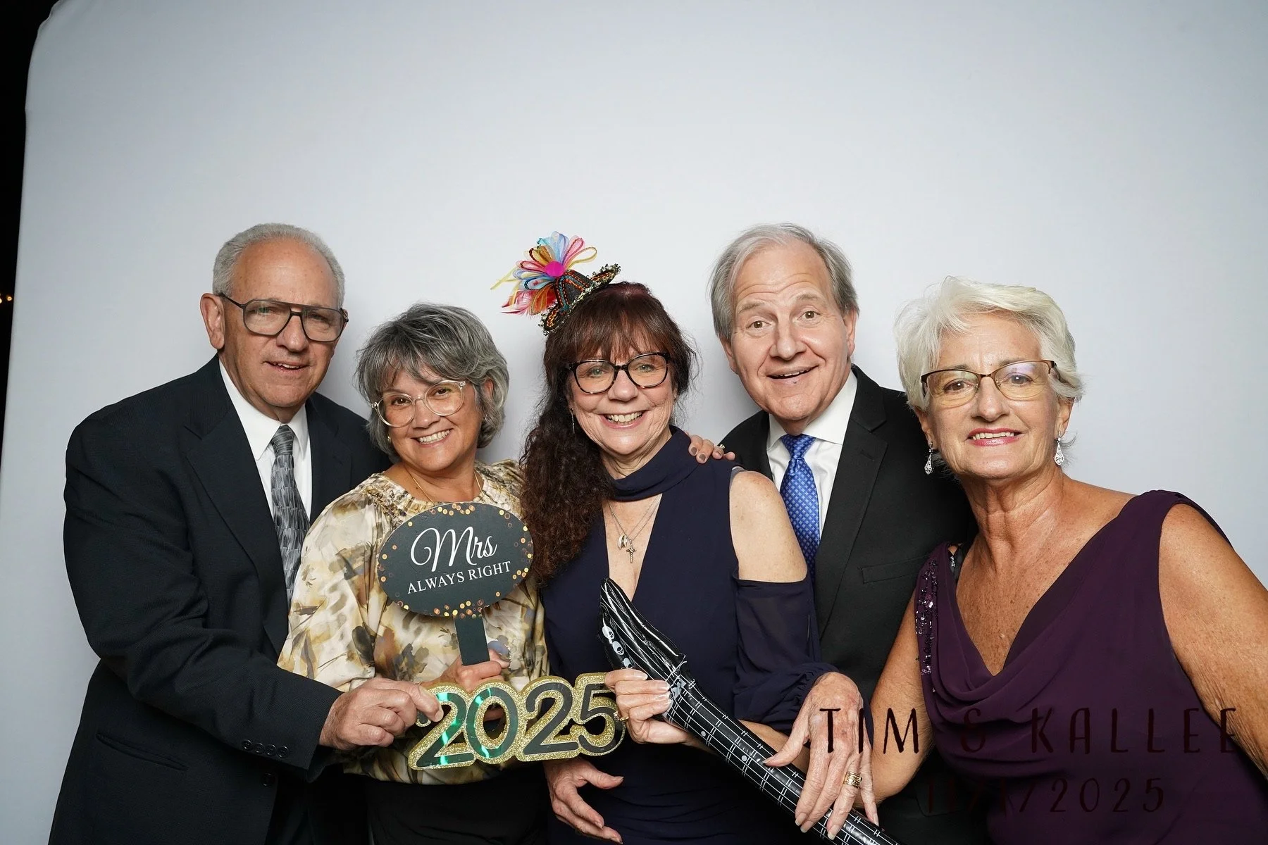 Six older adults dressed in formal attire at a celebration, holding signs that say 'Mrs ALWAYS RIGHT' and '2025', with a white background.