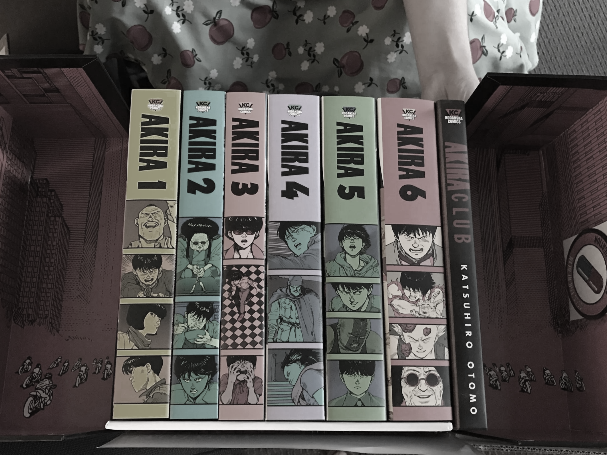 A box set of Akira manga volumes 1 through 6 with illustrated covers, featuring characters from the series, inside a pink and black box.