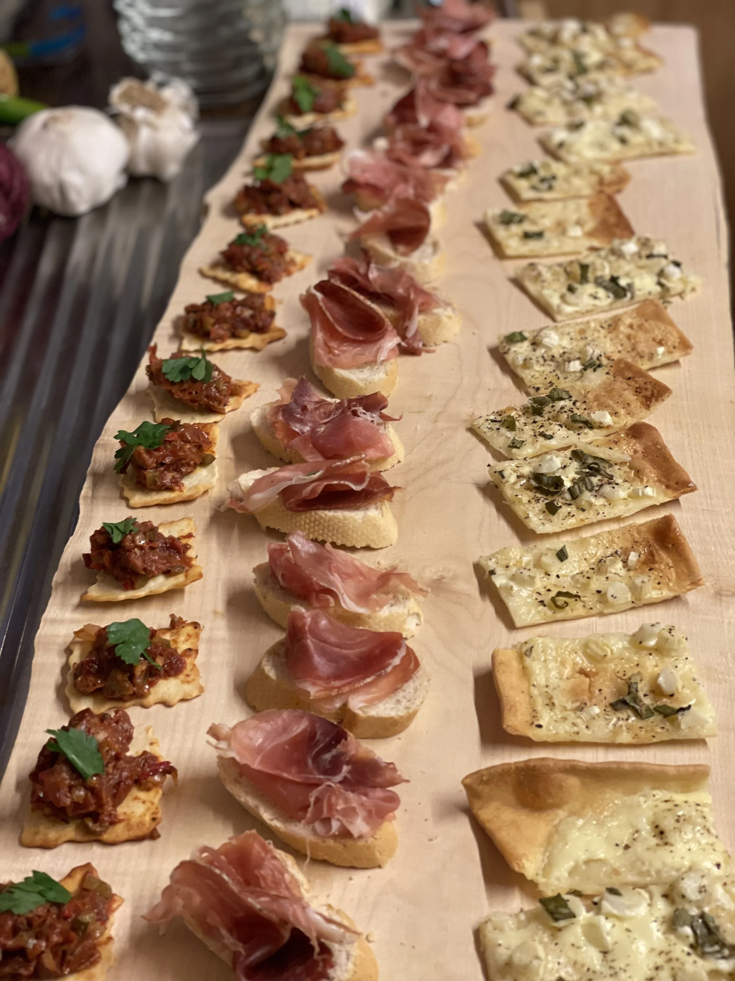 Verschiedene belegte kleine Apéro-Stücke und Canapés auf einem Holzbrett.