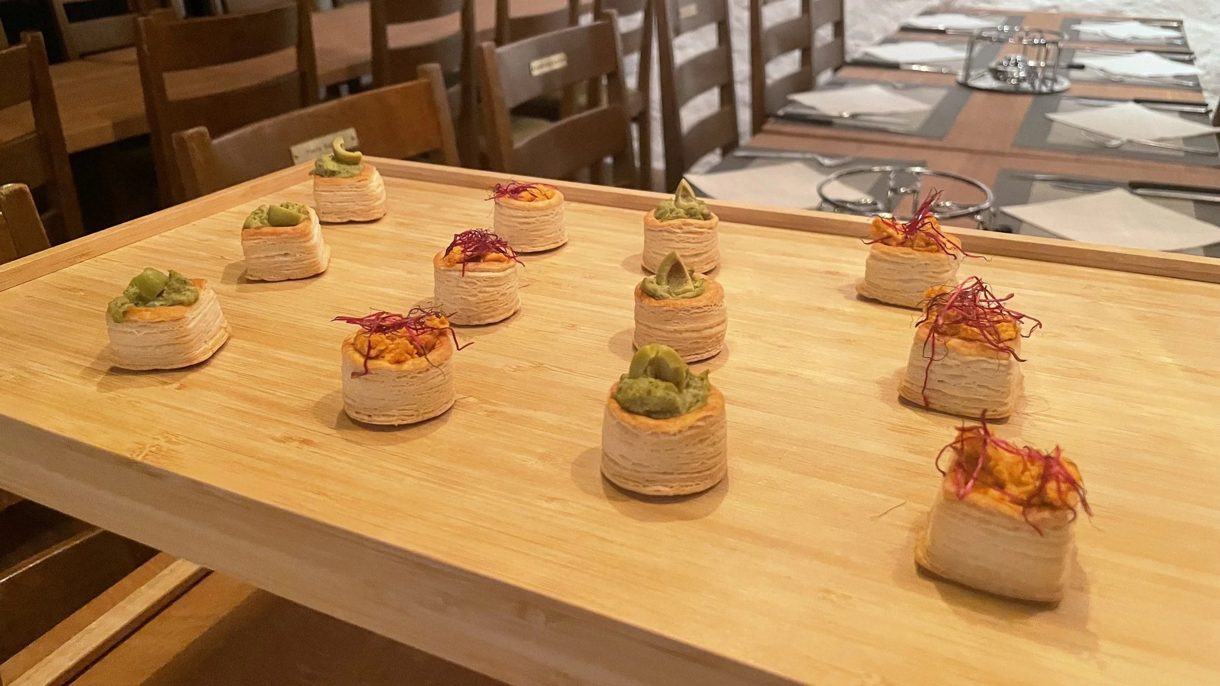 Mehrere kleine, runde Häppchen mit verschiedenen grünen und roten Toppings