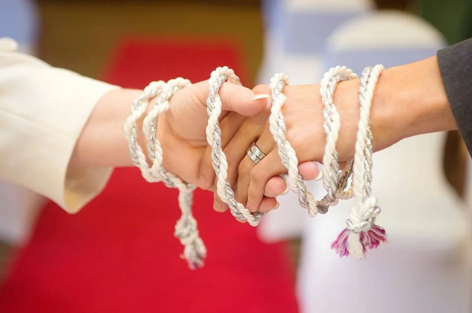 A handfasting: Two hands together with a rope wrapped around them symbolising a union, a marriage.