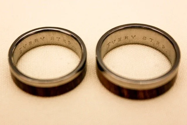 Two wedding rings, wood and metal, inscribed inside with the words 'Every Step'