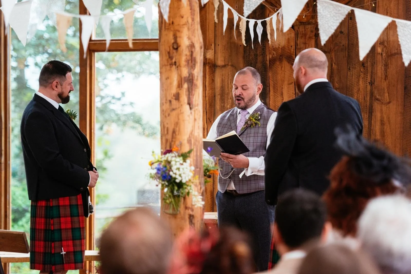 The celebrant reads from his script, stood between two kilted grooms