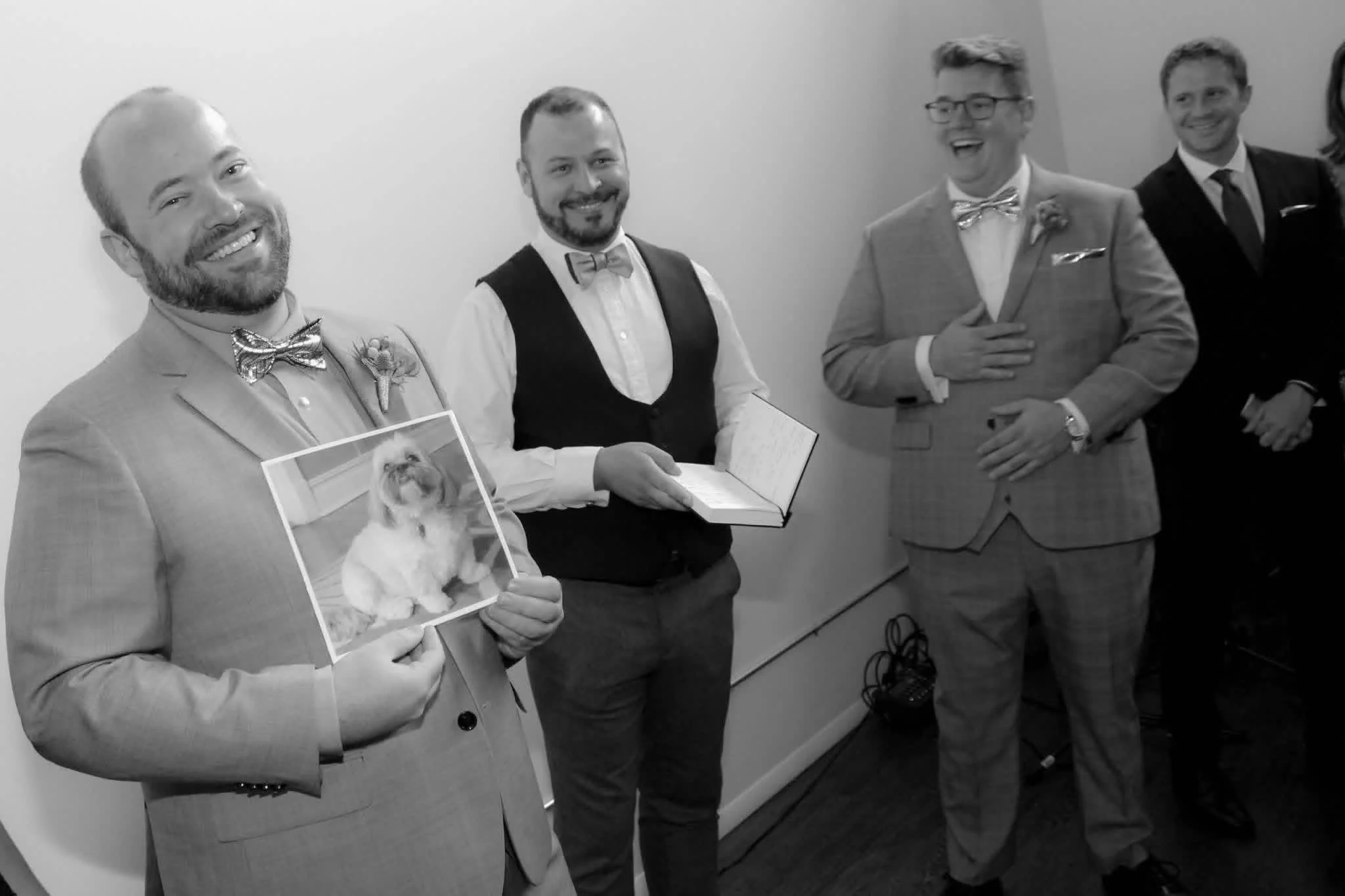 The celebrant stands between two grooms, one of which is holding a picture of their dog, the obvious 'missing guest'