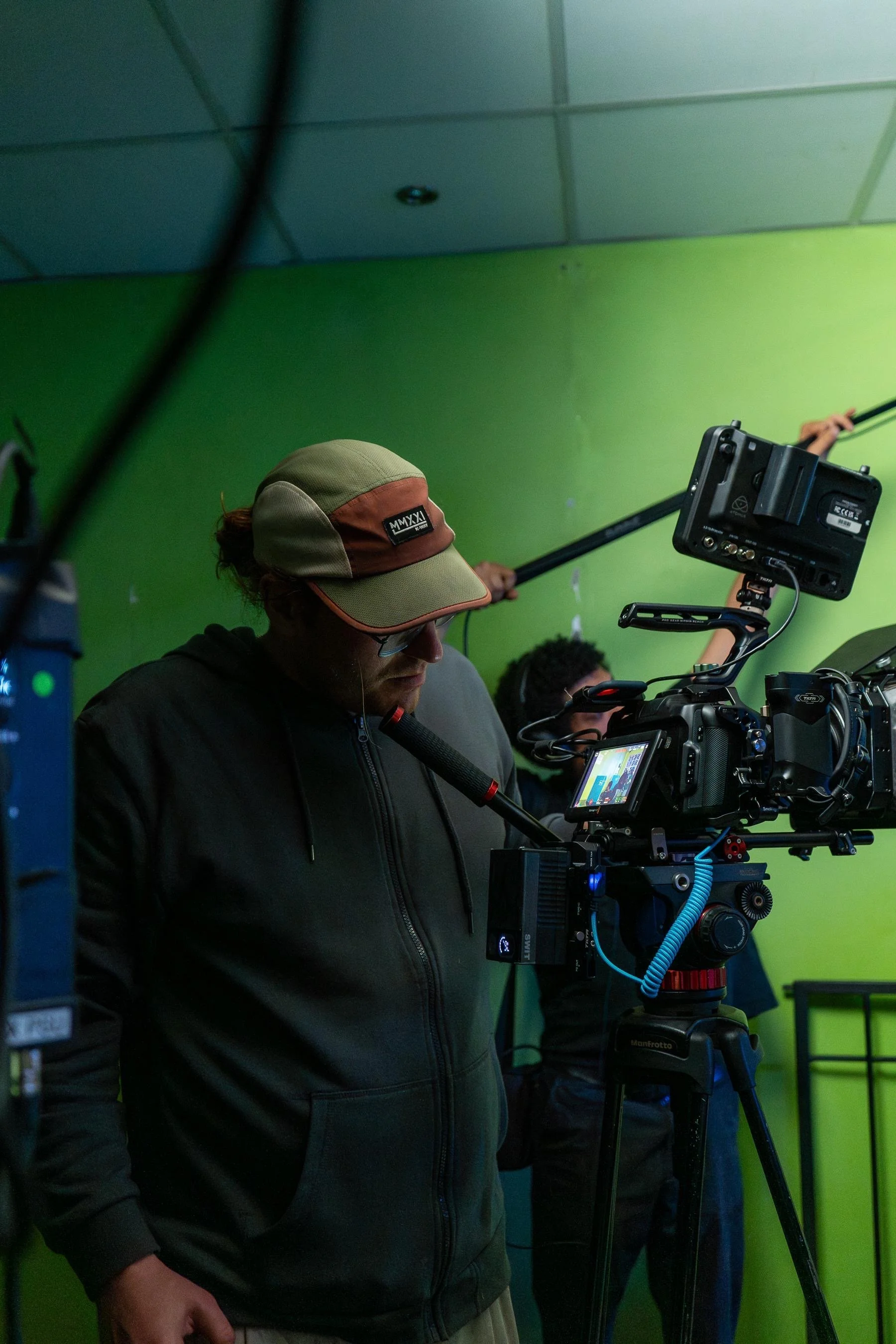 Emile Bosch operating a cinema camera on a narrative film set with other crew members in the background.