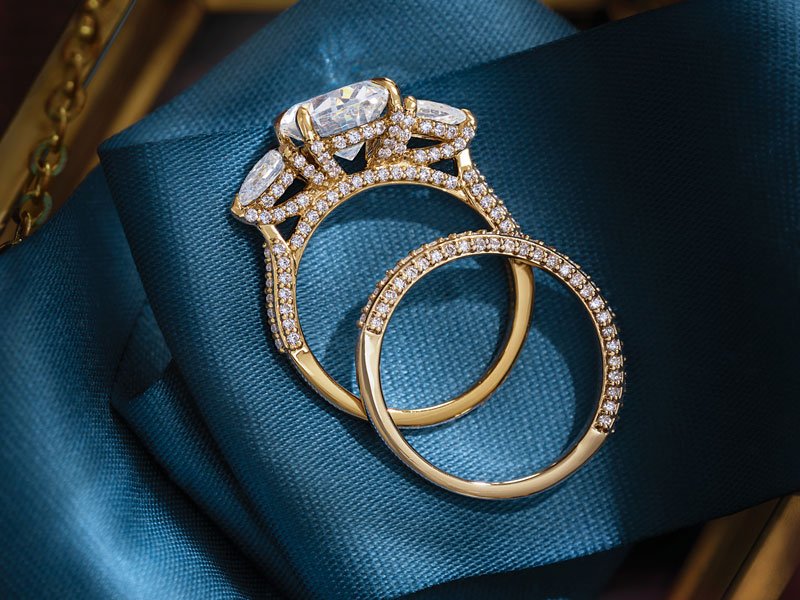 Two gold rings with diamonds on a blue satin fabric.