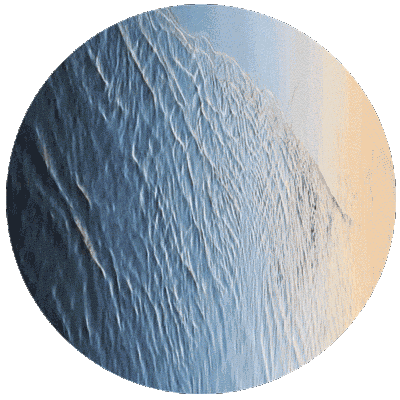 Close-up of water with ripples reflecting the sky, showing a gradient from blue to light pink.