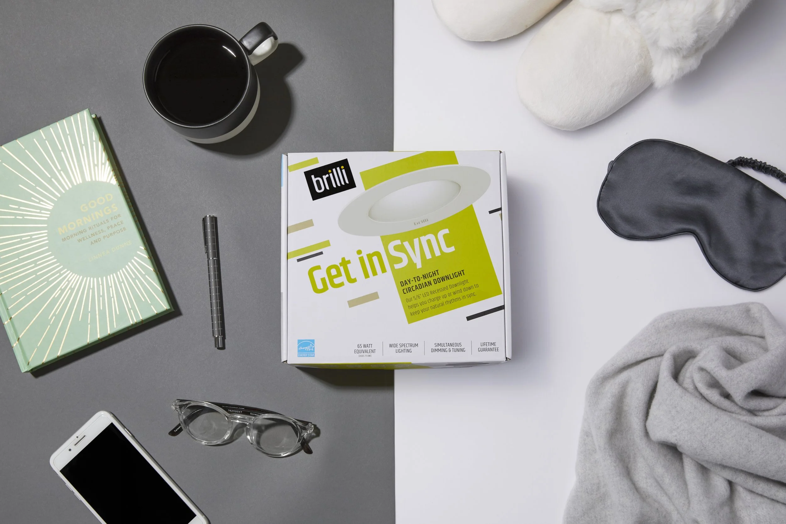 A divided image showing contrasting sides of a workspace or bedroom setup. The left side features a gray background with a coffee mug, a book titled 'Good Mornings,' a black pen, glasses, and a smartphone. The right side shows a white background with